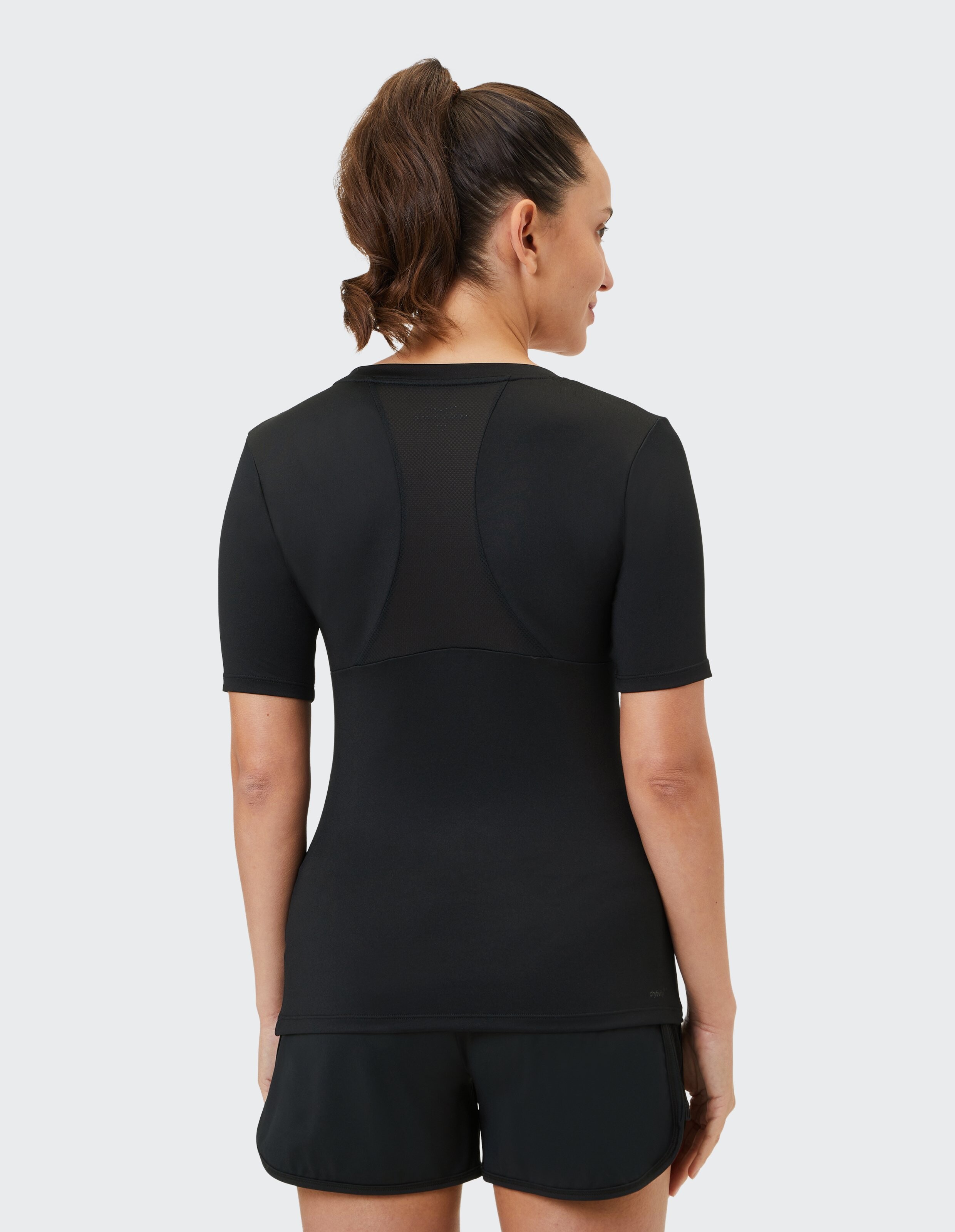 Rückansicht einer Frau in einem schwarzen Kurzarm-Top und Shorts, die ein elegantes Design zeigt.