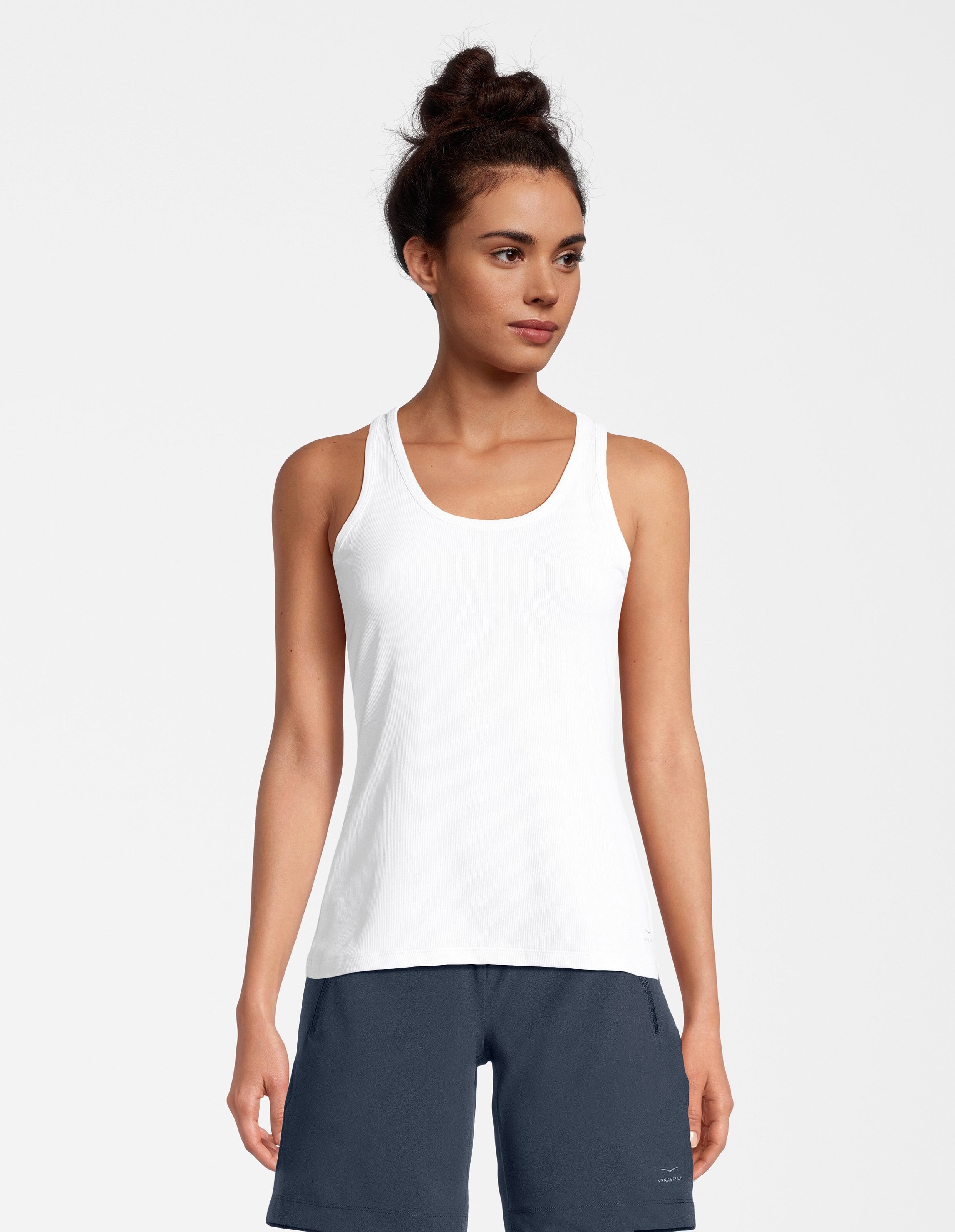 Frau trägt ein weißes, geripptes Tanktop, perfekt zum lässigen Sommer-Lounge.