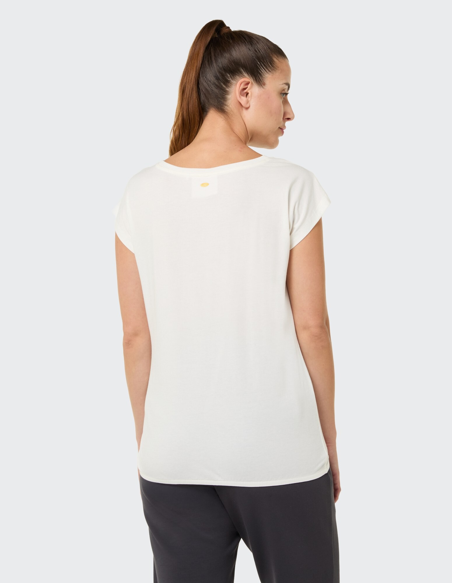 Rückansicht einer Frau, die ein weißes, lässiges T-Shirt trägt und eine entspannte Passform zeigt.