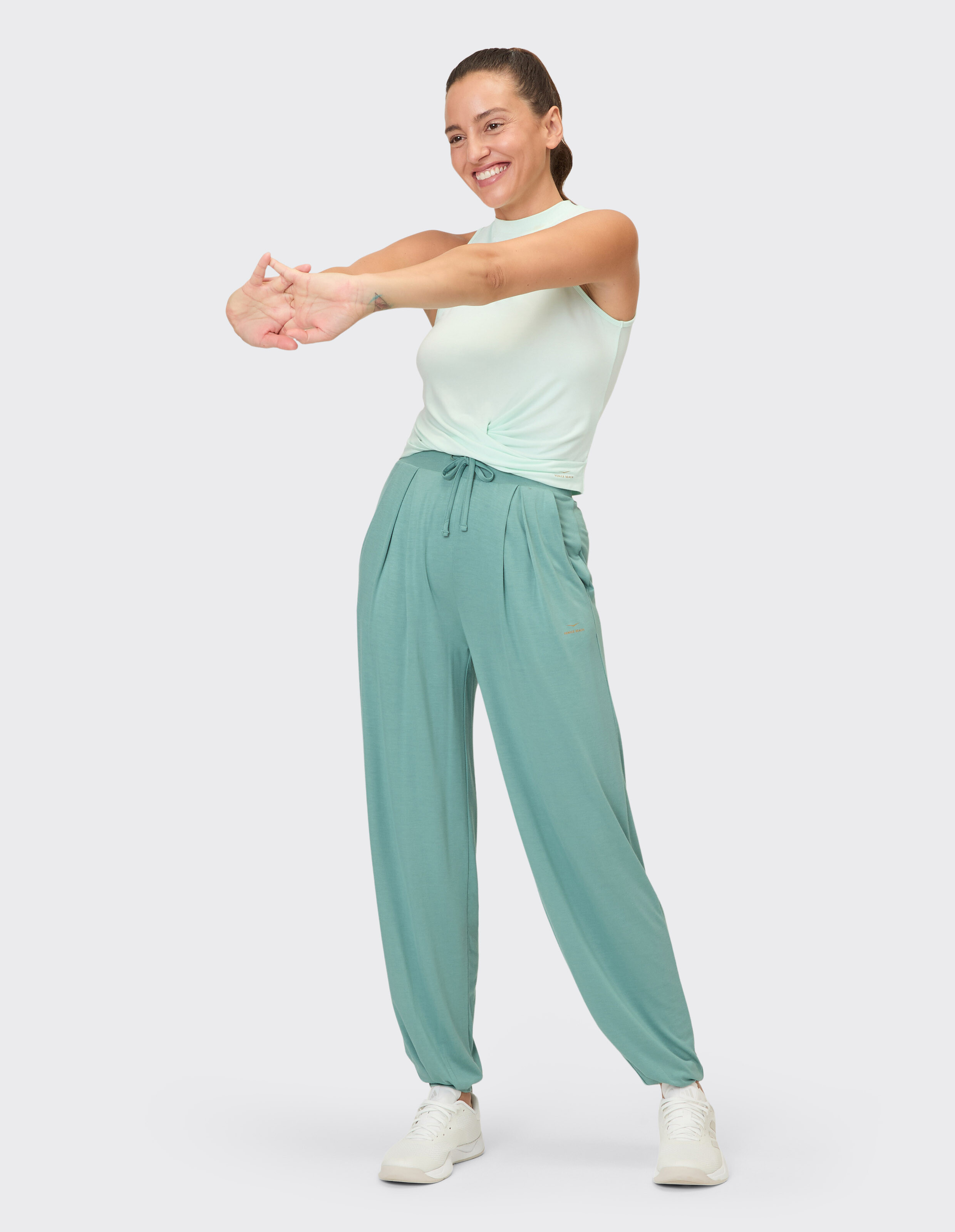 Frau trägt ein mintgrünes Tanktop und passende lässige Jogginghosen für einen bequemen Look.