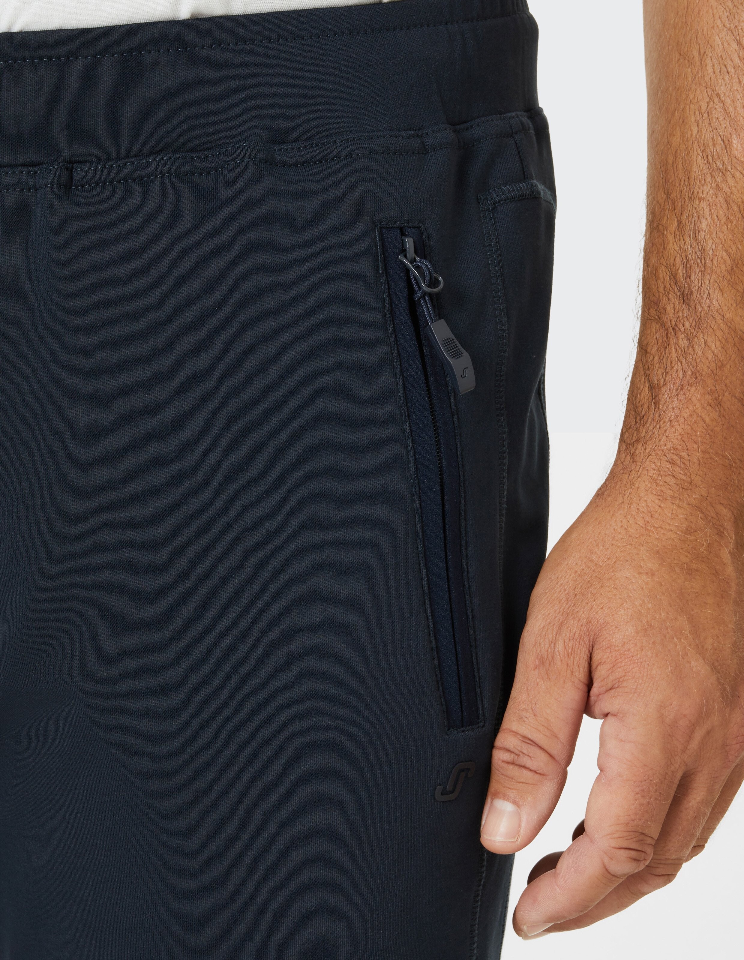 Schwarze Jogginghose mit elastischem Bund und zwei seitlichen Reißverschlusstaschen, aus weichem Stoff, gerade geschnitten.