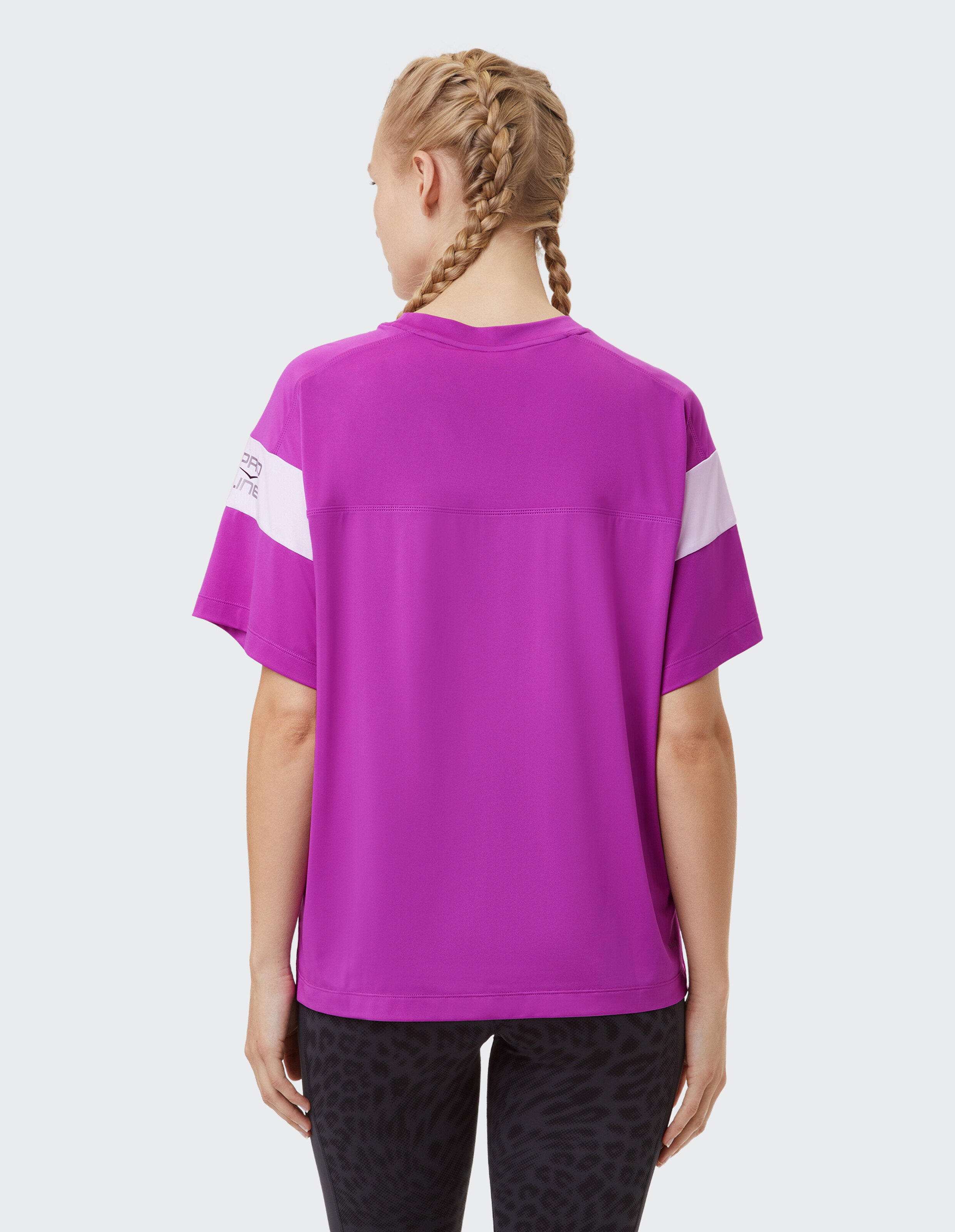 Frau trägt ein leuchtend lila lässiges T-Shirt mit weißen Ärmelstreifen.