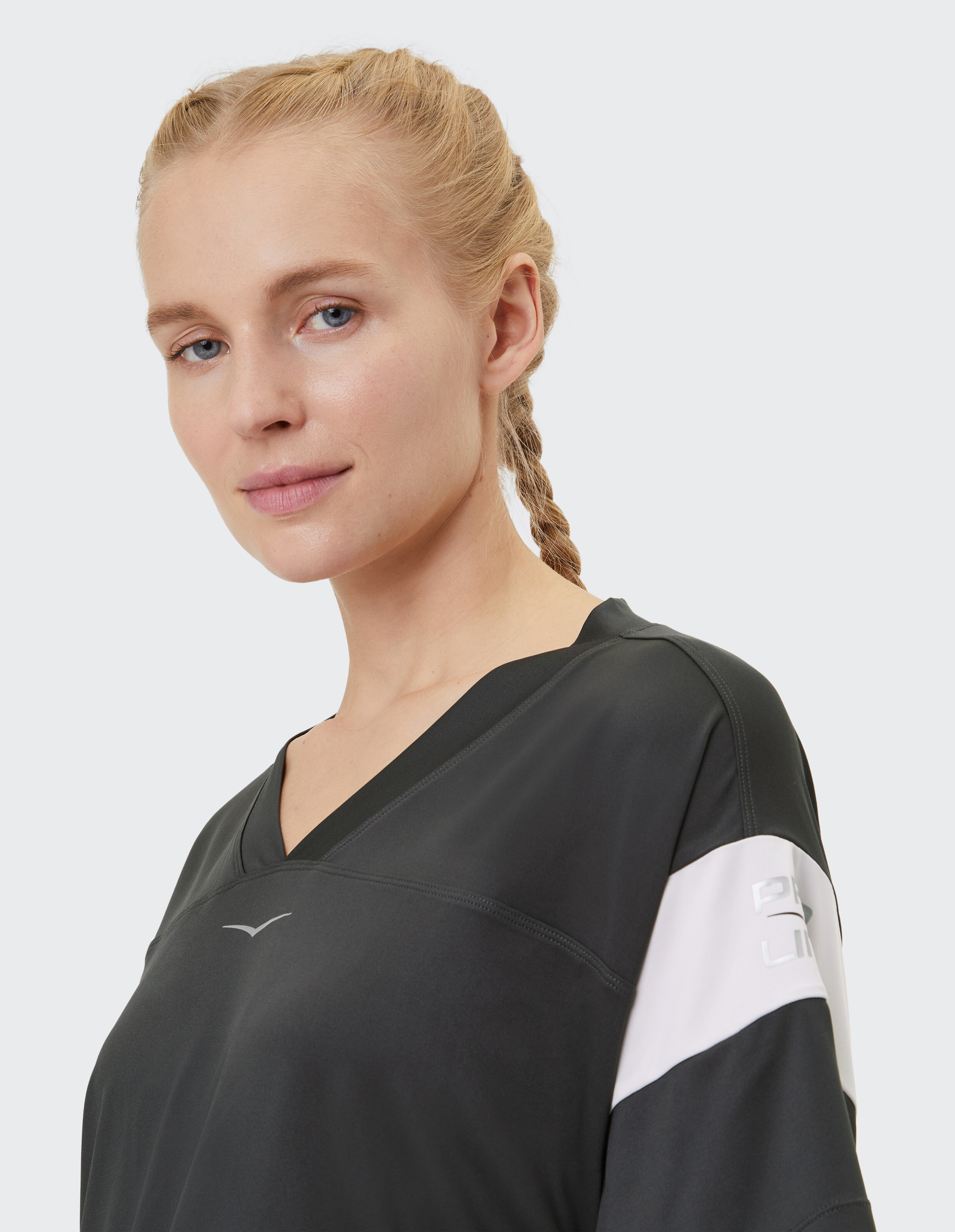 Nahaufnahme einer Frau in einem schwarzen, lässigen Top mit V-Ausschnitt und sportlichem Design.