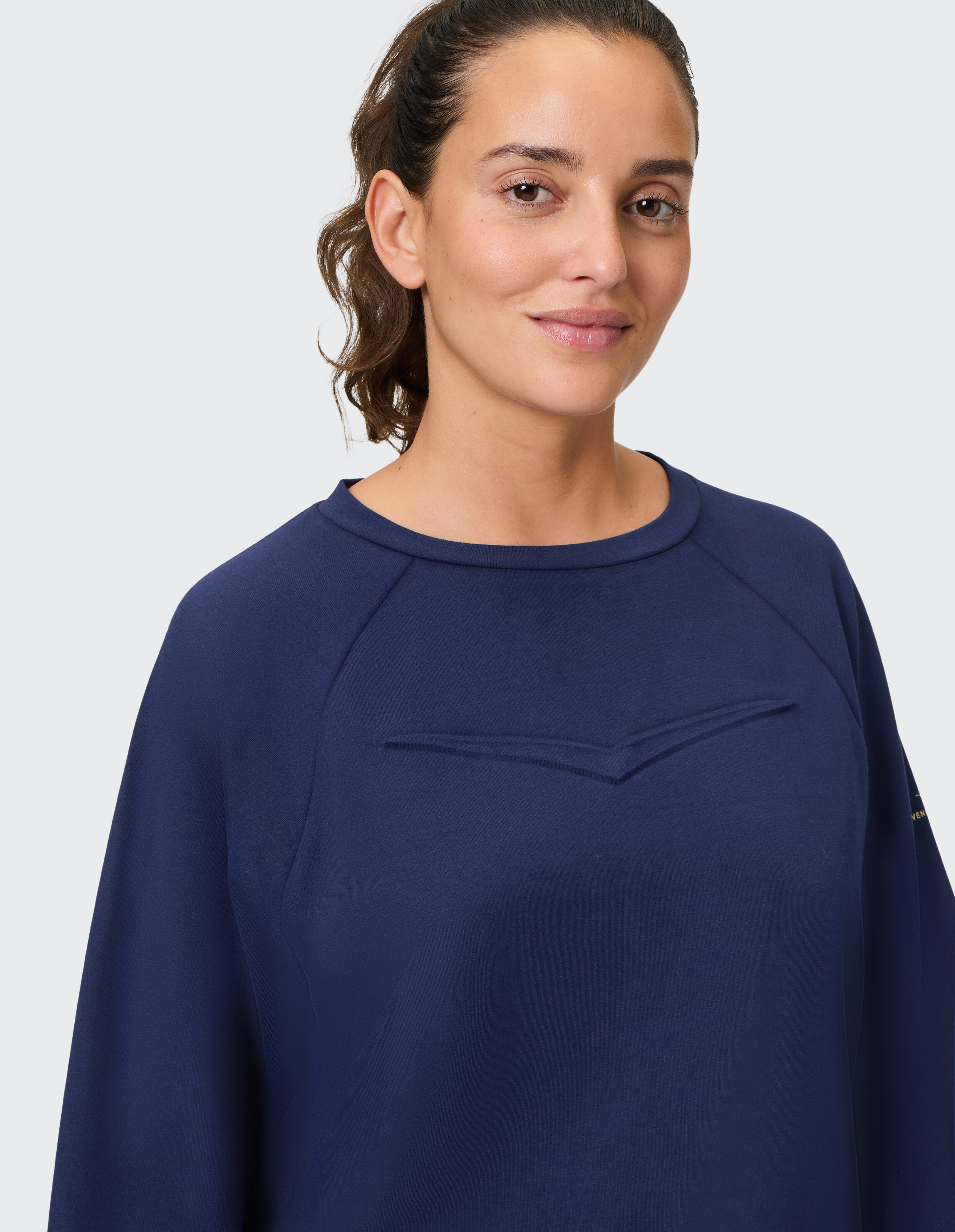 Frau trägt ein gemütliches marineblaues Freizeit-Sweatshirt mit Raglanärmeln.