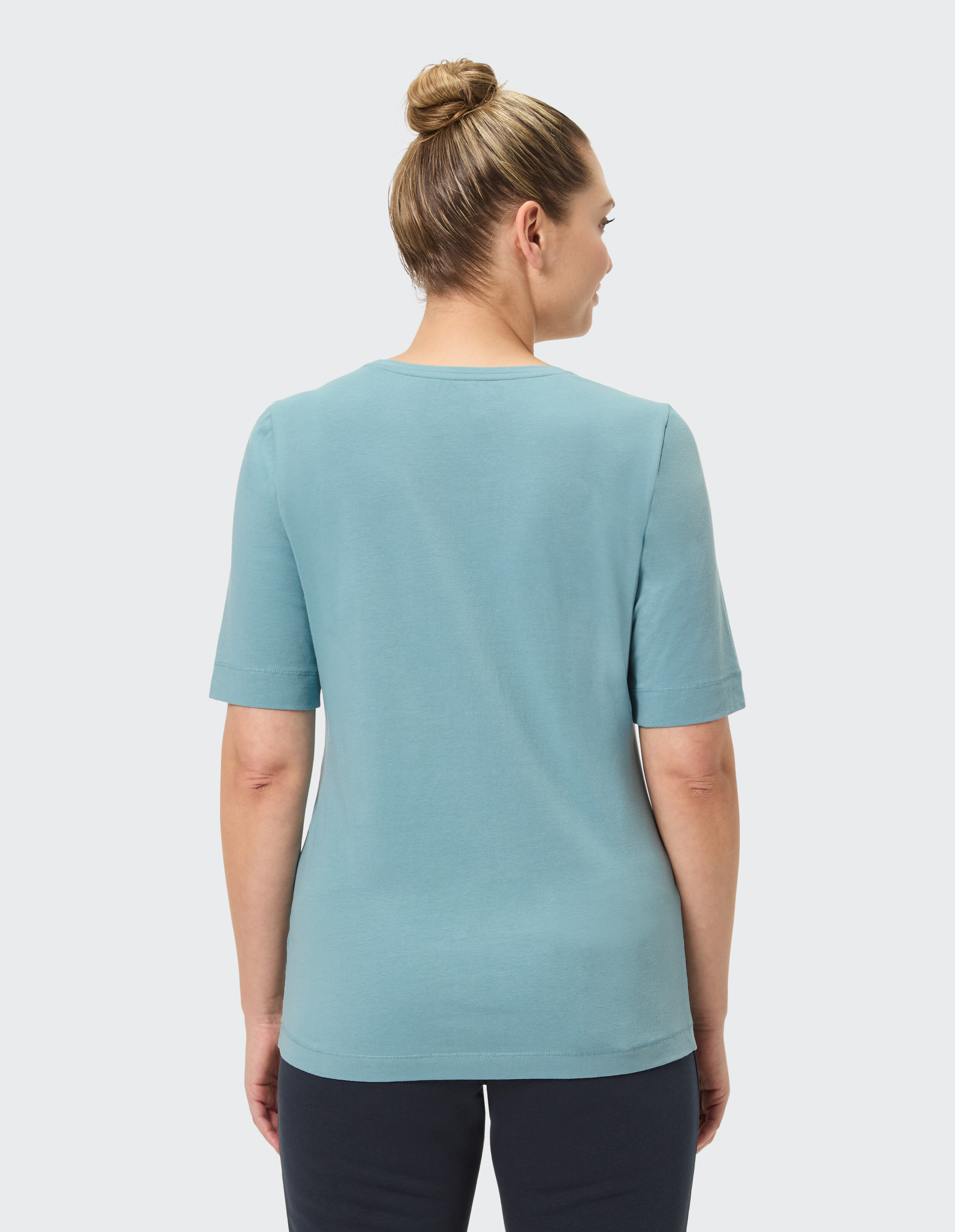 Rückansicht einer Frau, die ein hellblaues Freizeit-T-Shirt trägt, perfekt zum Entspannen.