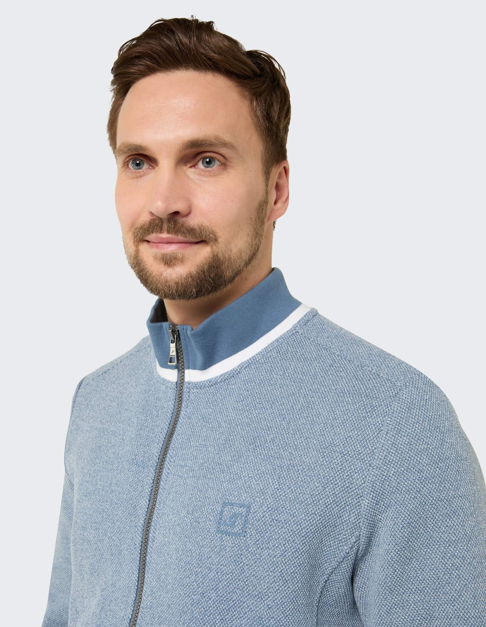 Mann trägt einen hellblauen Pullover mit Reißverschluss und weißem Kragendetail.