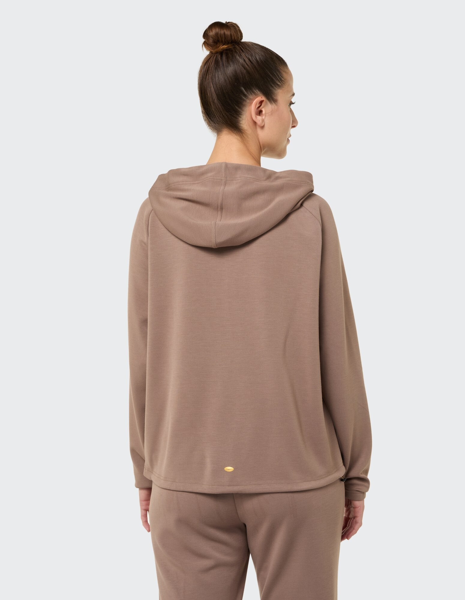 Rückansicht einer Frau in einem gemütlichen braunen Kapuzenpullover, perfekt für Freizeitkleidung.