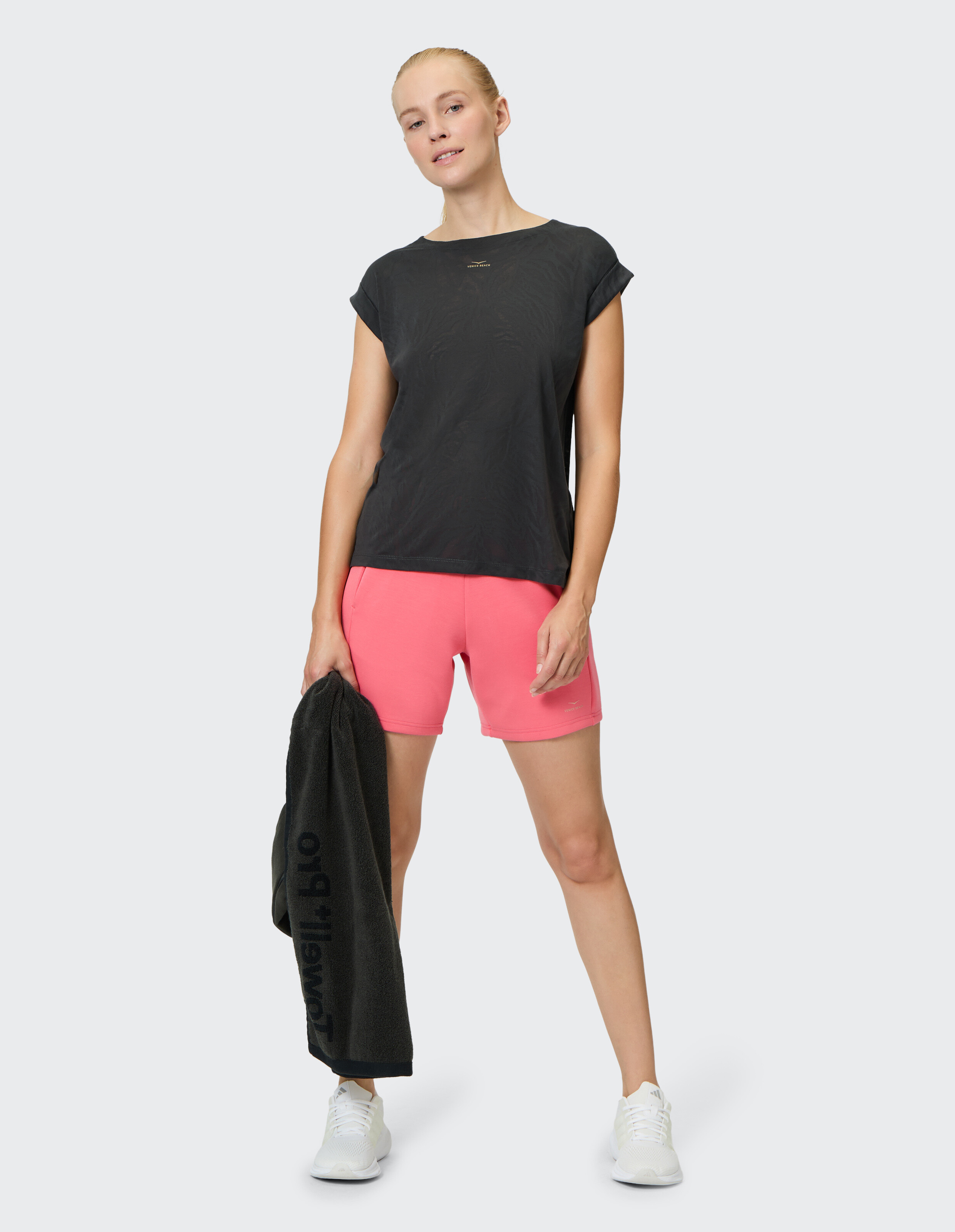 Frau trägt ein schwarzes Venice Beach Kurzarmshirt Tirara und rosa Shorts.
