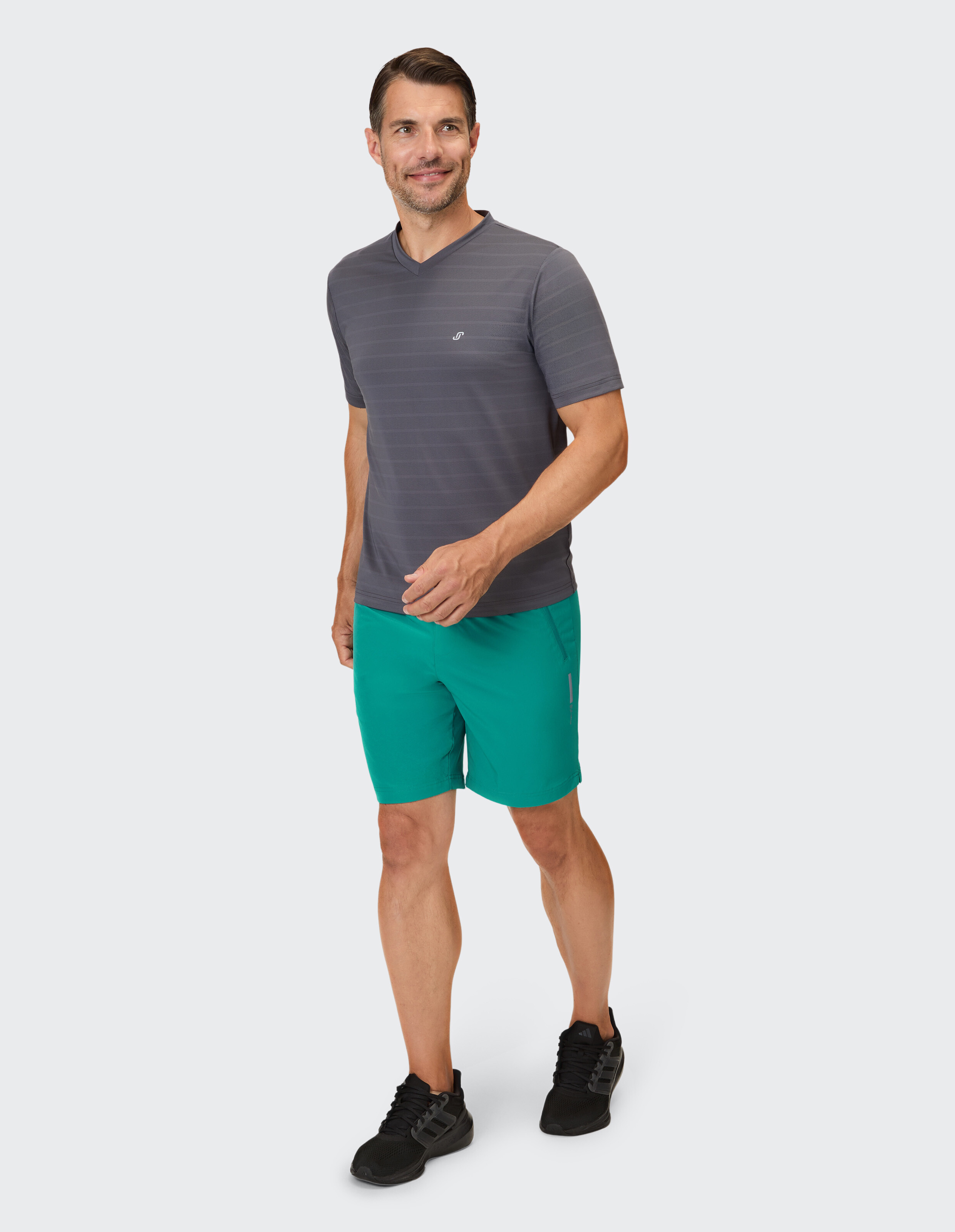 Mann in grau gestreiftem Hemd mit V-Ausschnitt und blaugrünen Shorts, perfekt für Freizeitausflüge.