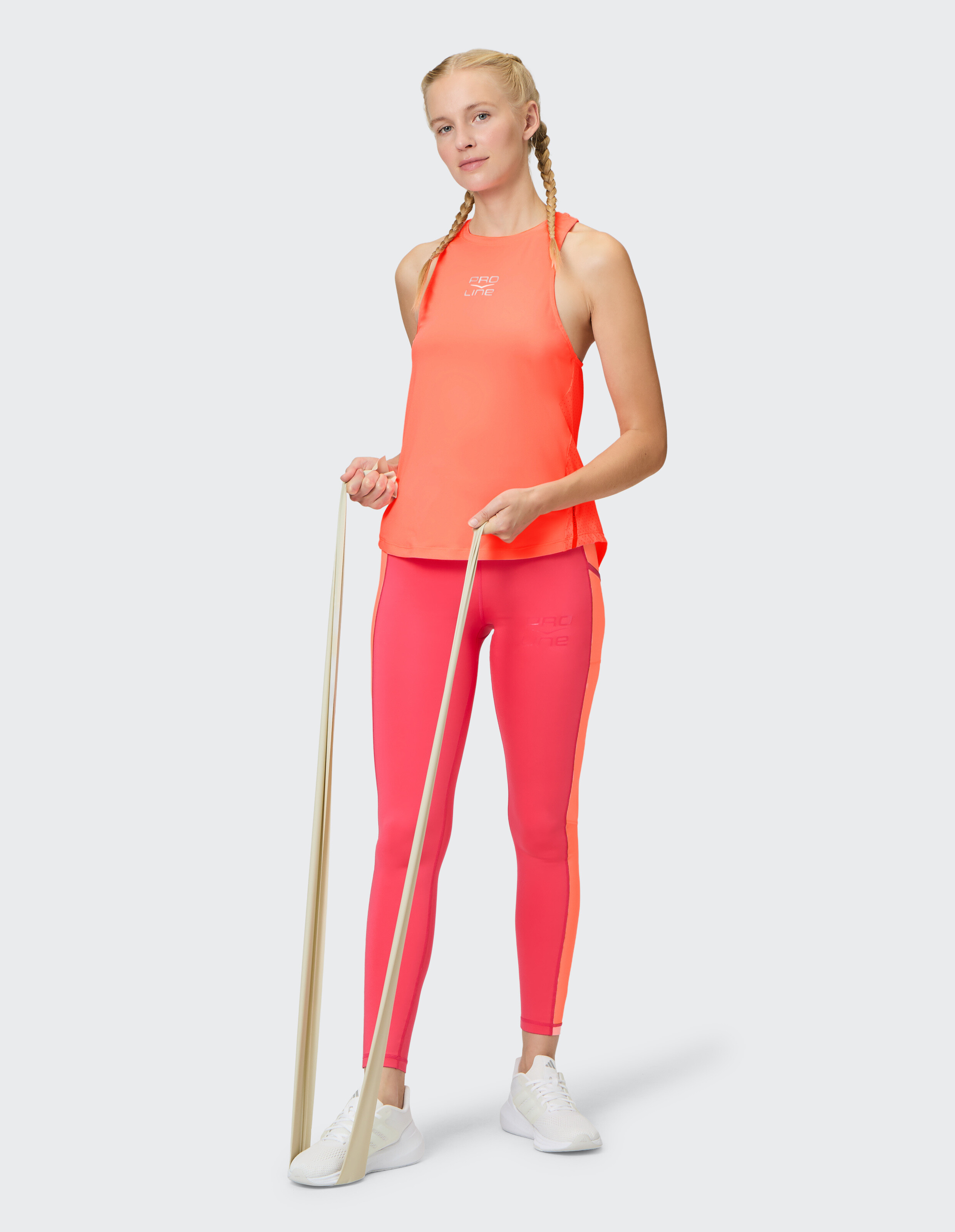 Frau trägt ein leuchtend orangefarbenes Venice Beach-Tanktop und rosa Leggings beim Training.