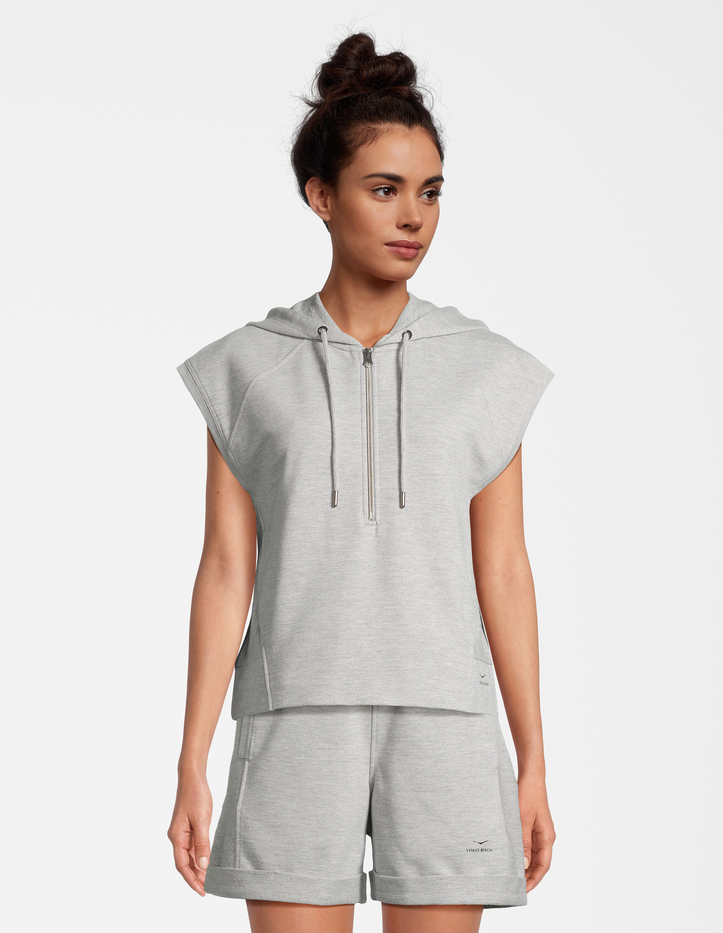 Frau trägt einen gemütlichen grauen ärmellosen Kapuzenpullover und passende Shorts für lässige Loungewear.