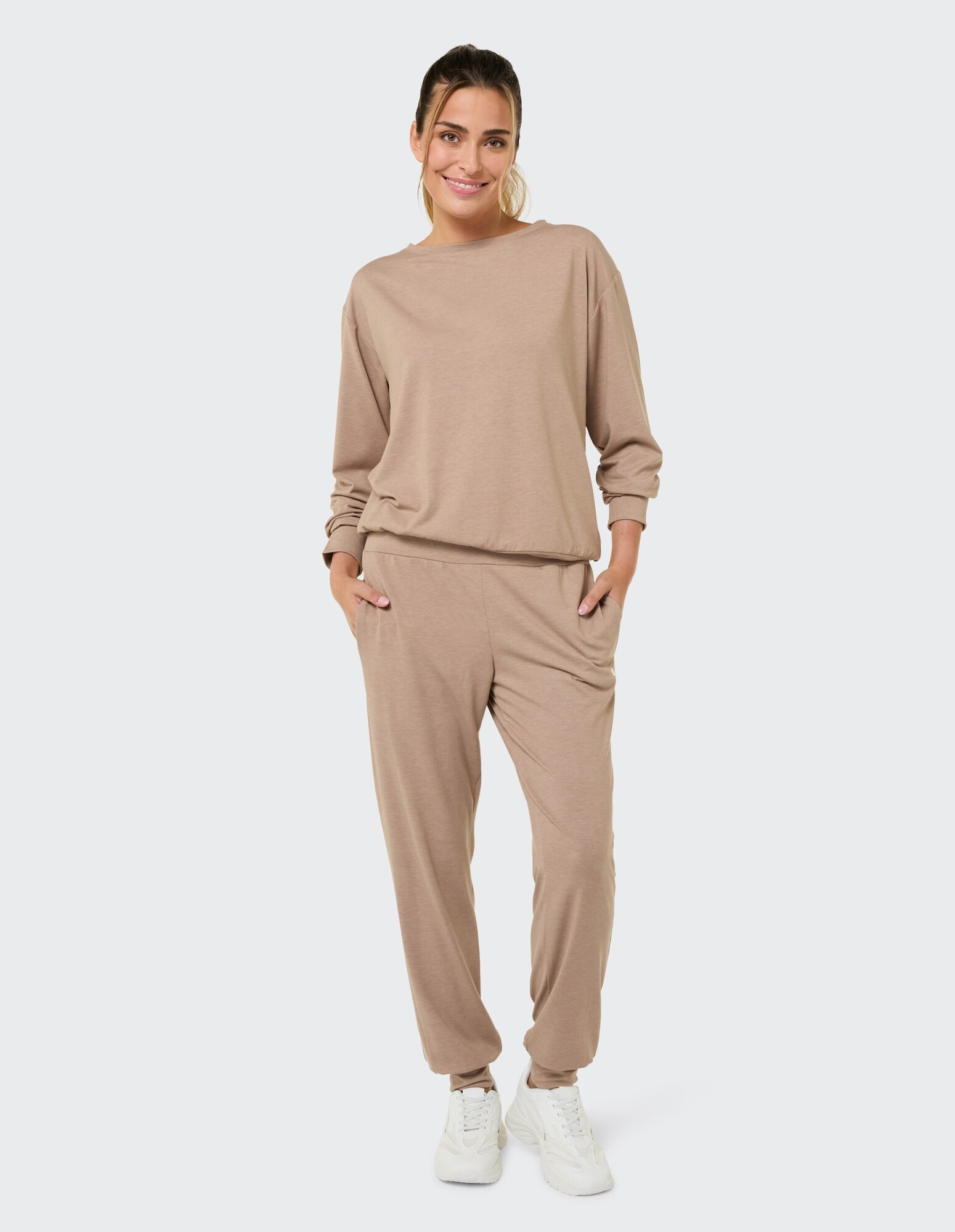 Frau in gemütlichem beigem Loungewear-Set mit langen Ärmeln und Jogginghose.