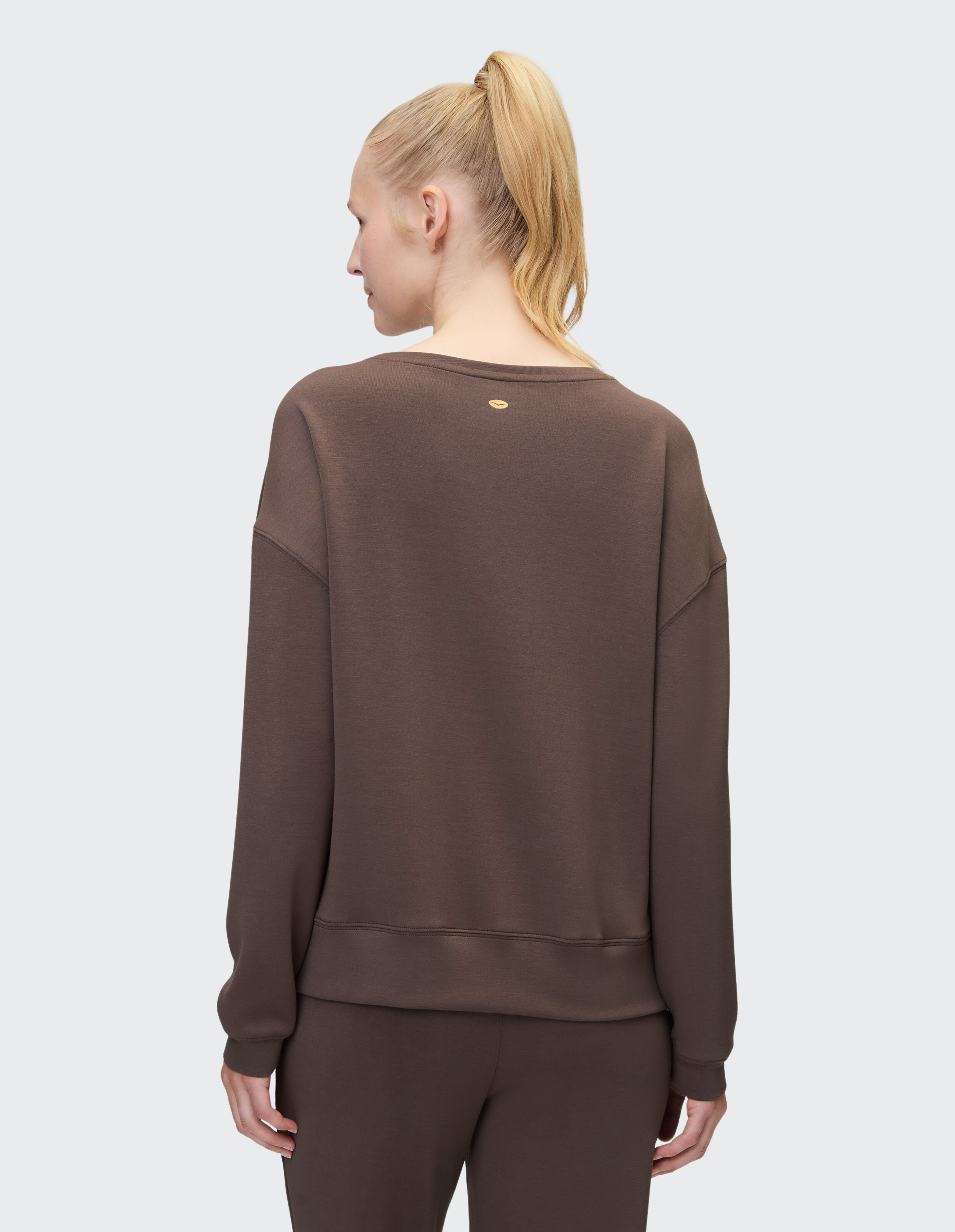 Rückansicht einer Frau in einem braunen, kuscheligen Sweatshirt, perfekt für Freizeitkleidung.