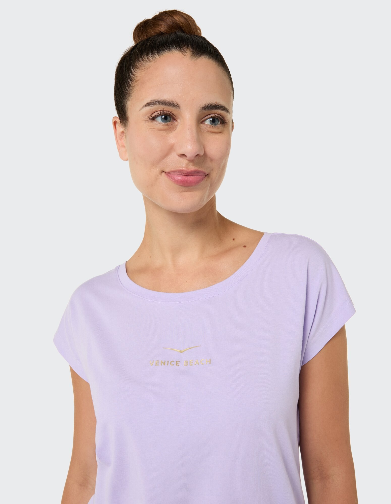 Frau trägt ein hellviolettes T-Shirt mit „Venice Beach“-Logo im lässigen Stil.