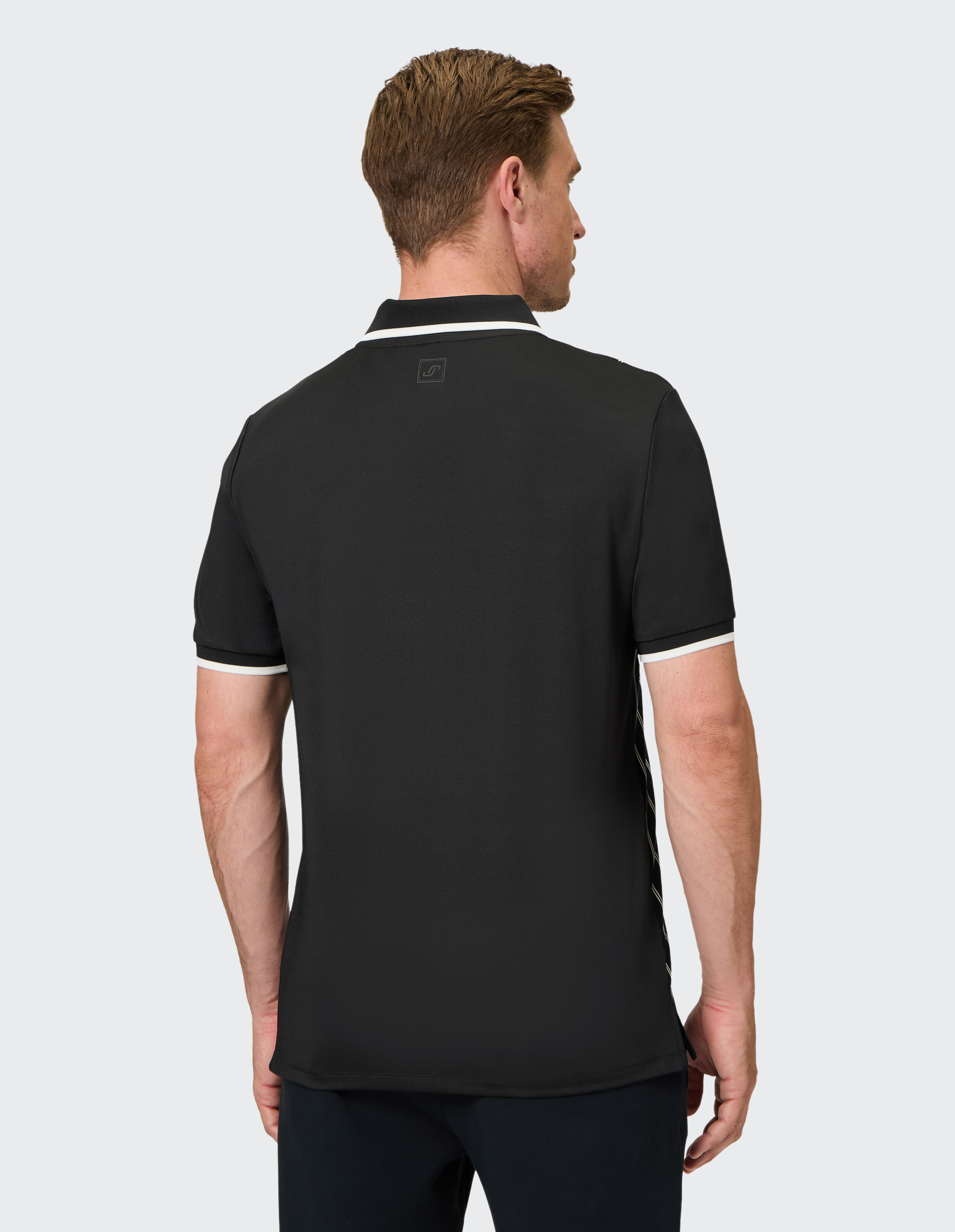 Rückansicht eines Mannes, der ein schwarzes Poloshirt mit weißen Akzenten trägt.