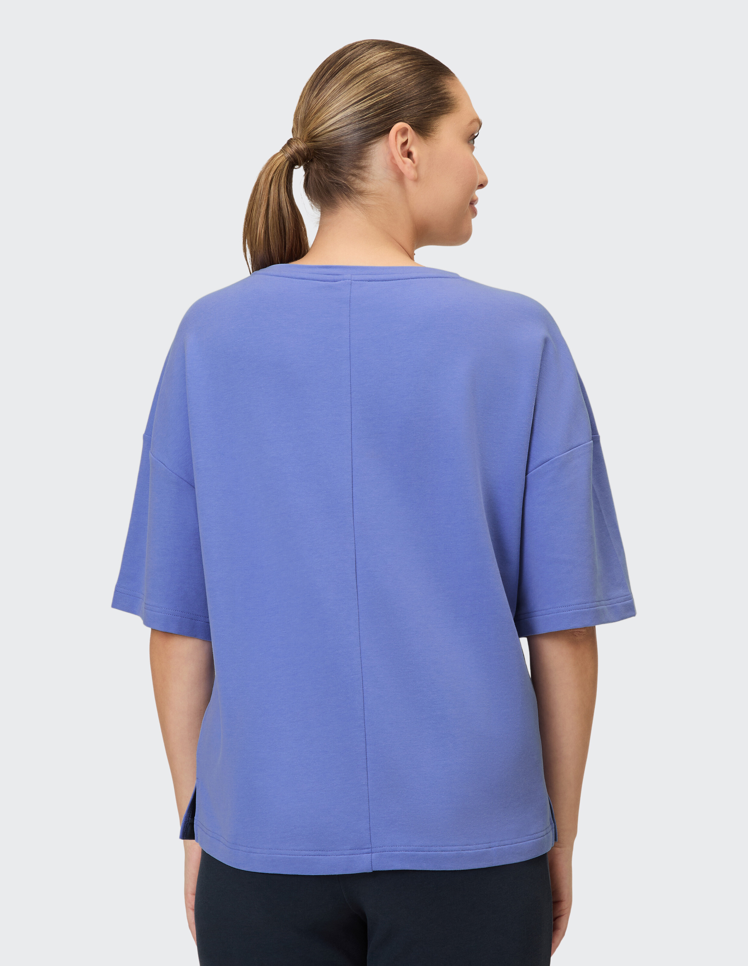 Rückansicht einer Frau in einem locker sitzenden lavendelfarbenen T-Shirt, perfekt für Freizeitkleidung.