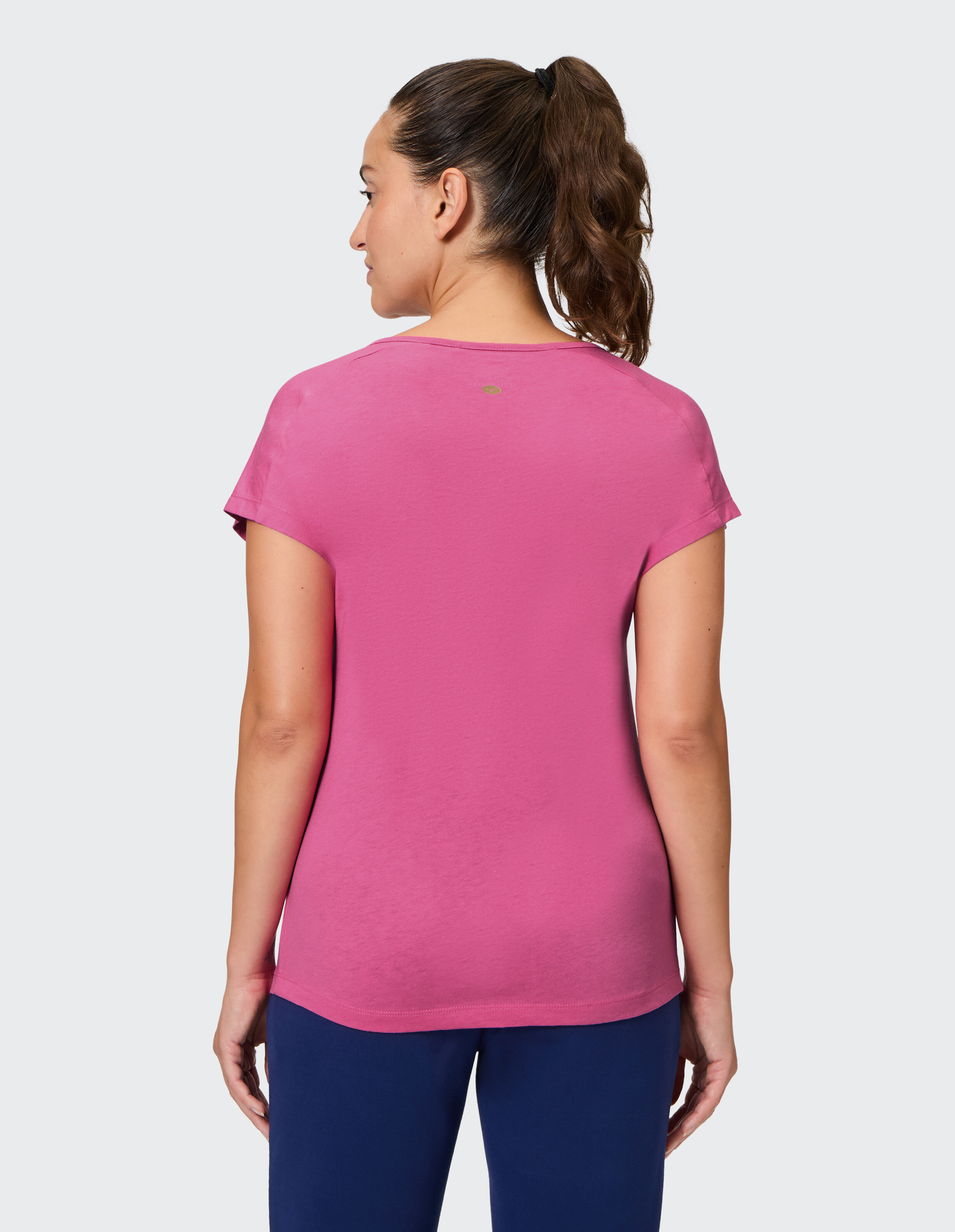 Frau trägt ein gemütliches rosafarbenes Freizeit-T-Shirt, Rückansicht, perfekt zum Faulenzen oder Reisen.