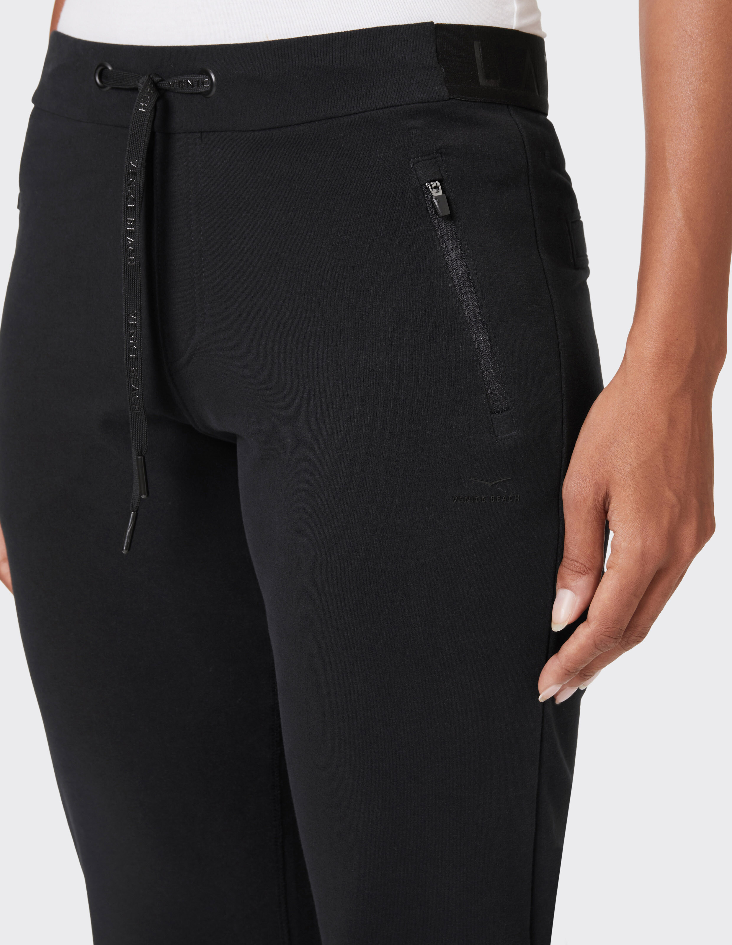 Schwarze, lässige Lounge-Hose mit Kordelzug in der Taille und Reißverschlusstaschen.
