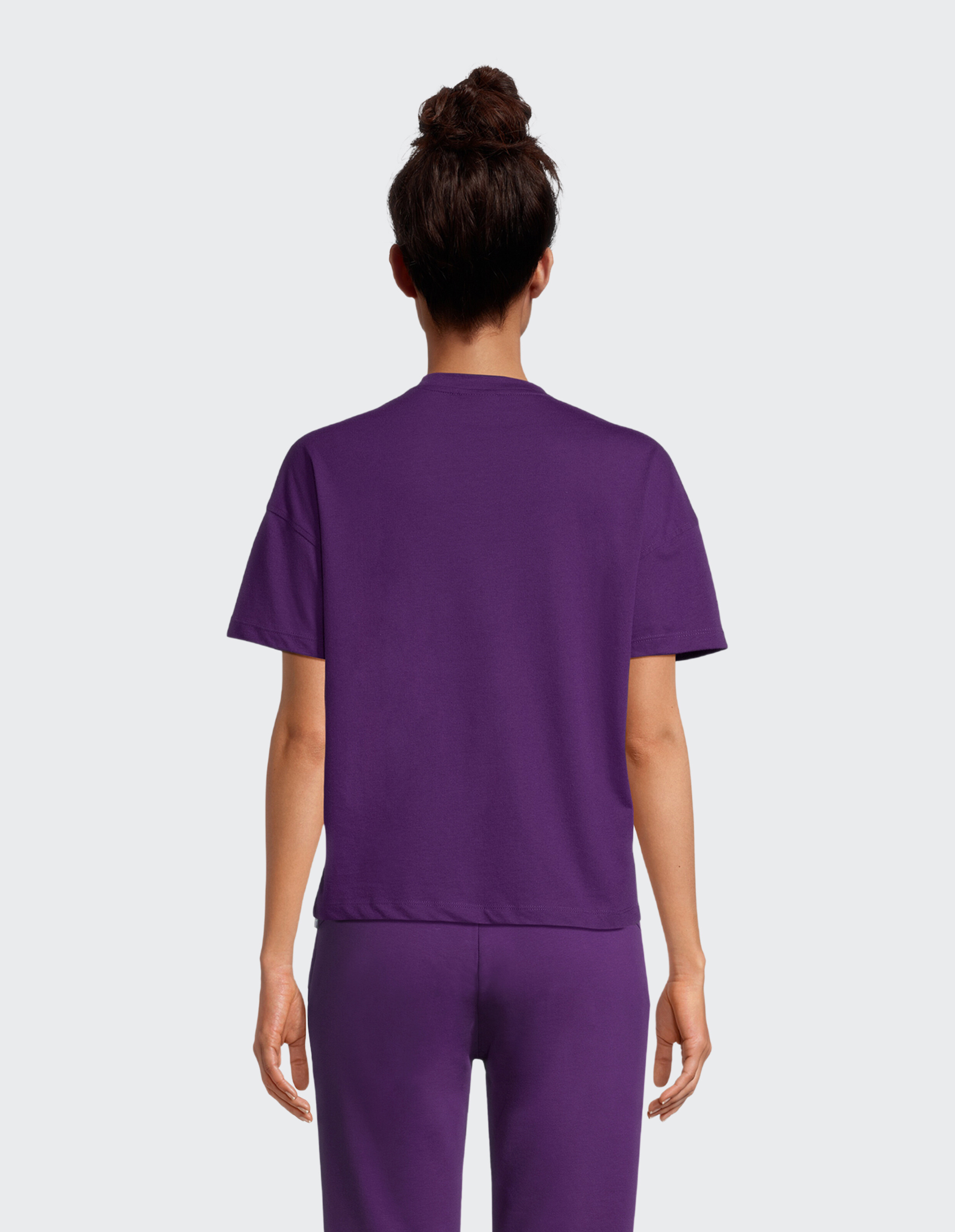 Rückansicht einer Frau, die ein lila Freizeit-T-Shirt und eine passende Hose trägt.