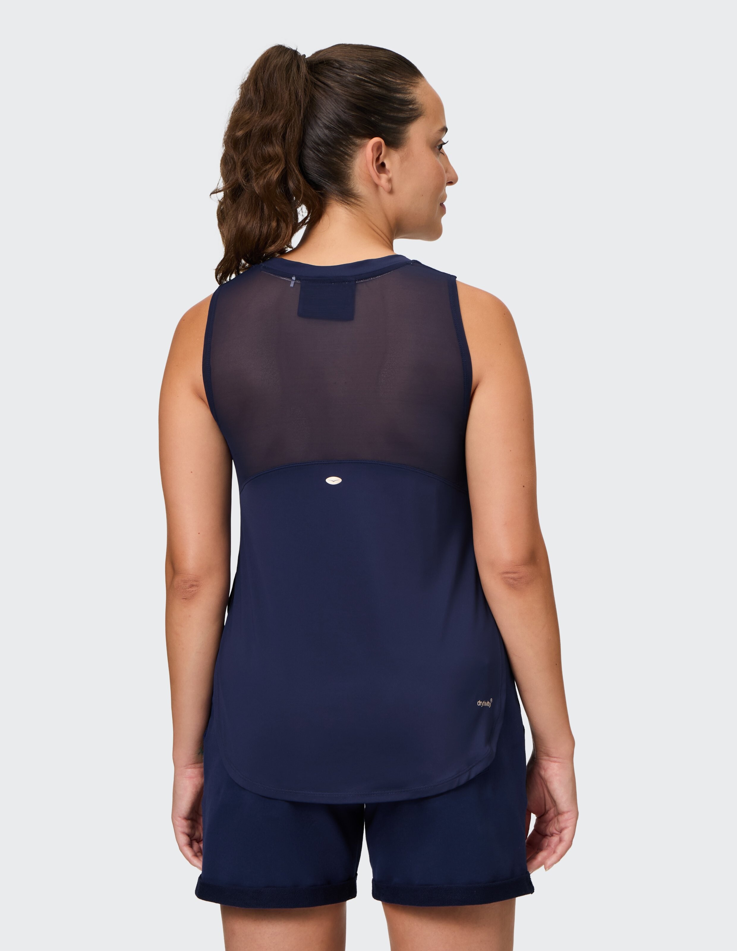 Frau trägt ein marineblaues, ärmelloses Sport-Tanktop mit Mesh-Detail am Rücken.