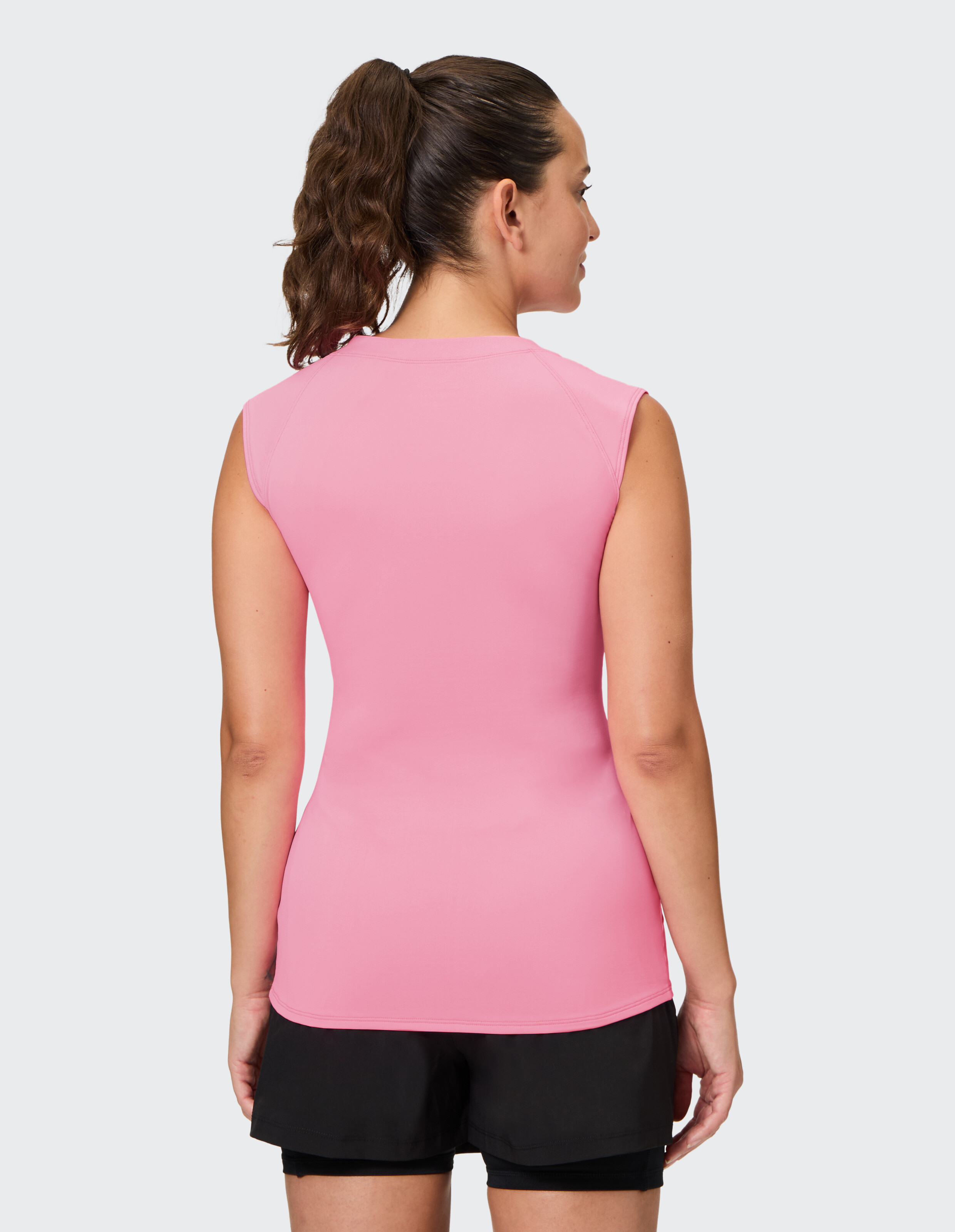 Rückansicht einer Frau, die ein rosa ärmelloses Top und schwarze Shorts trägt.