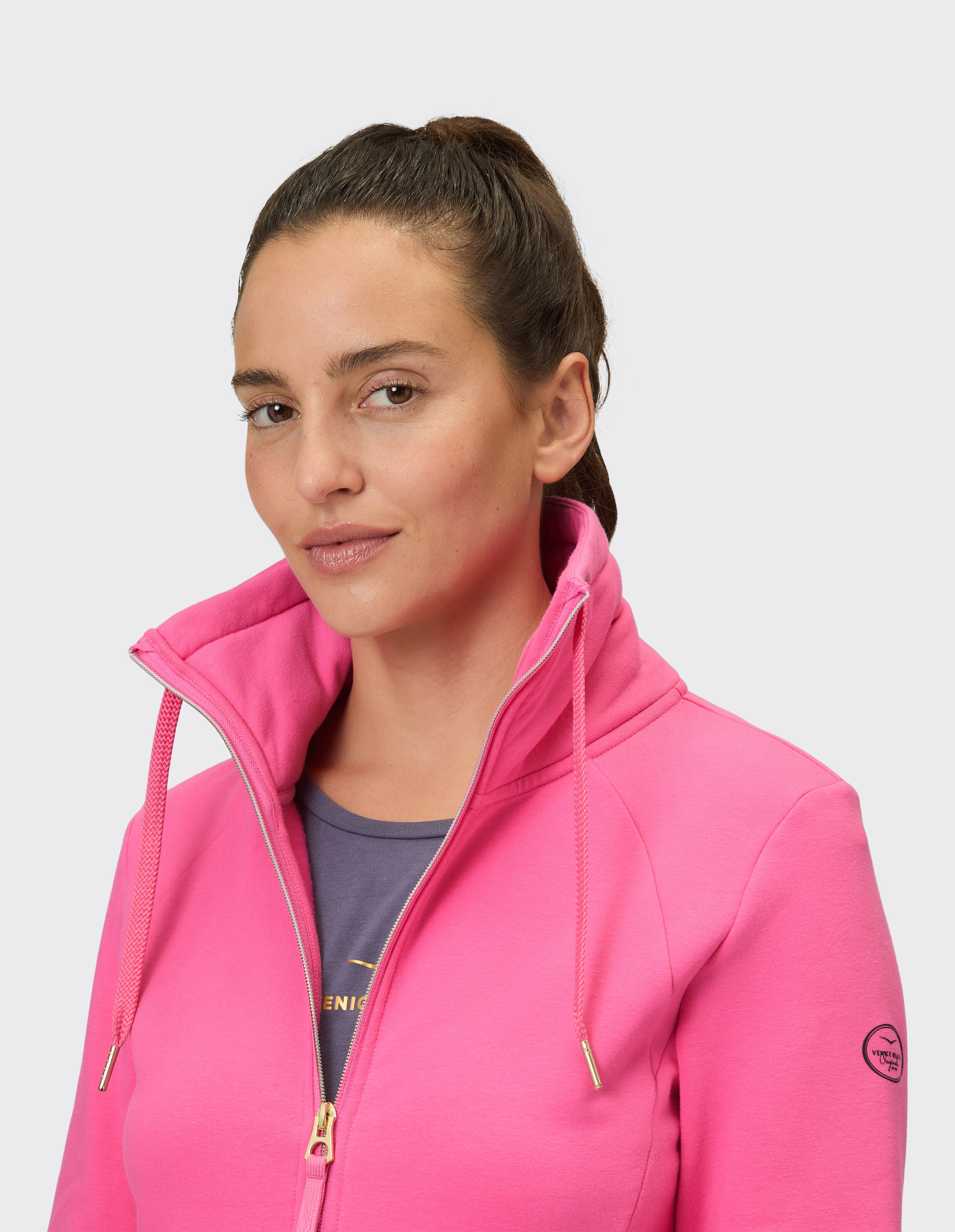 Nahaufnahme einer Frau in einem rosa Kapuzenpullover mit Reißverschluss, die einen lässigen und stilvollen Look zeigt.