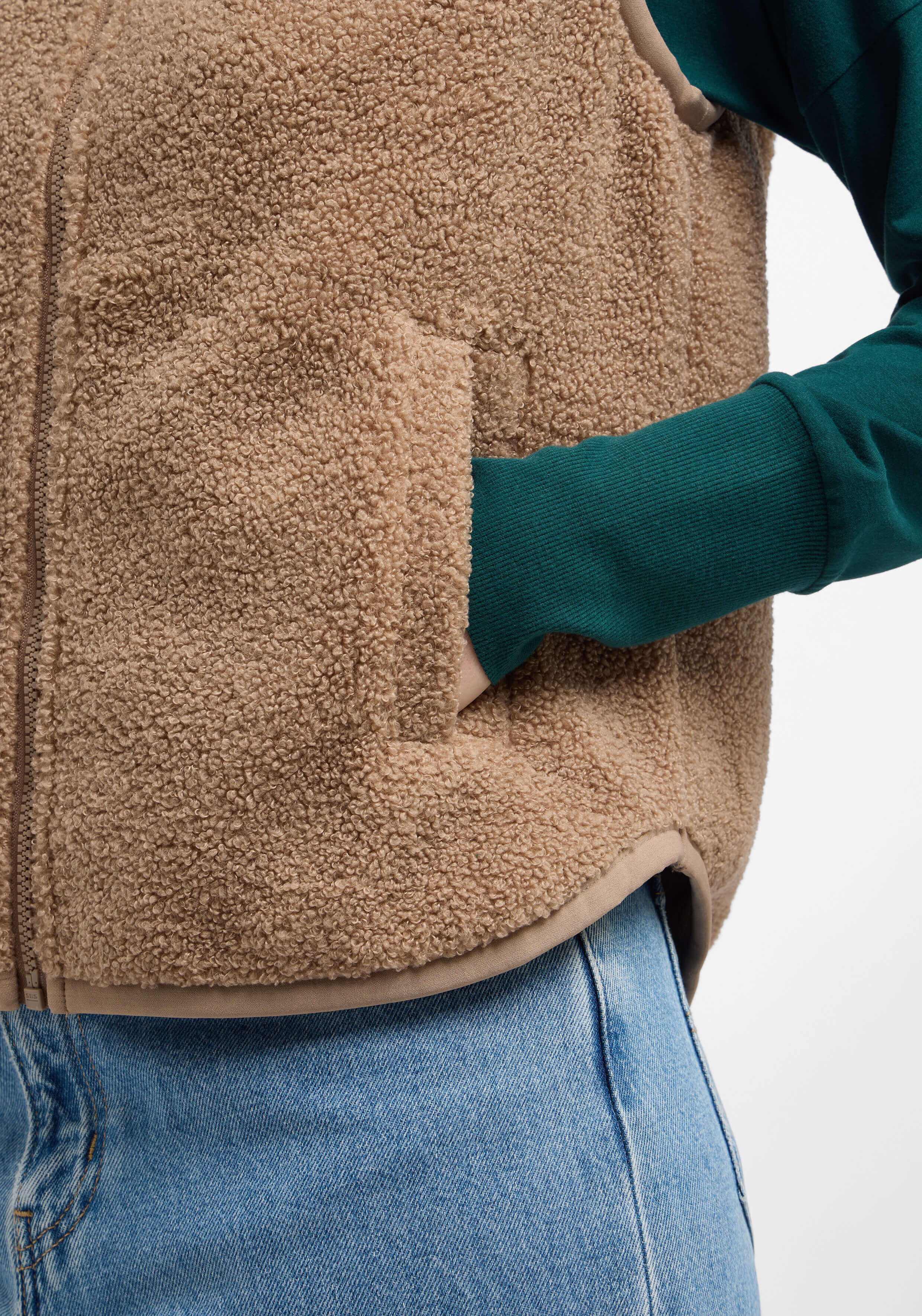 Kuschelige beige Fleeceweste mit Taschen, gepaart mit einem grünen Langarmshirt.