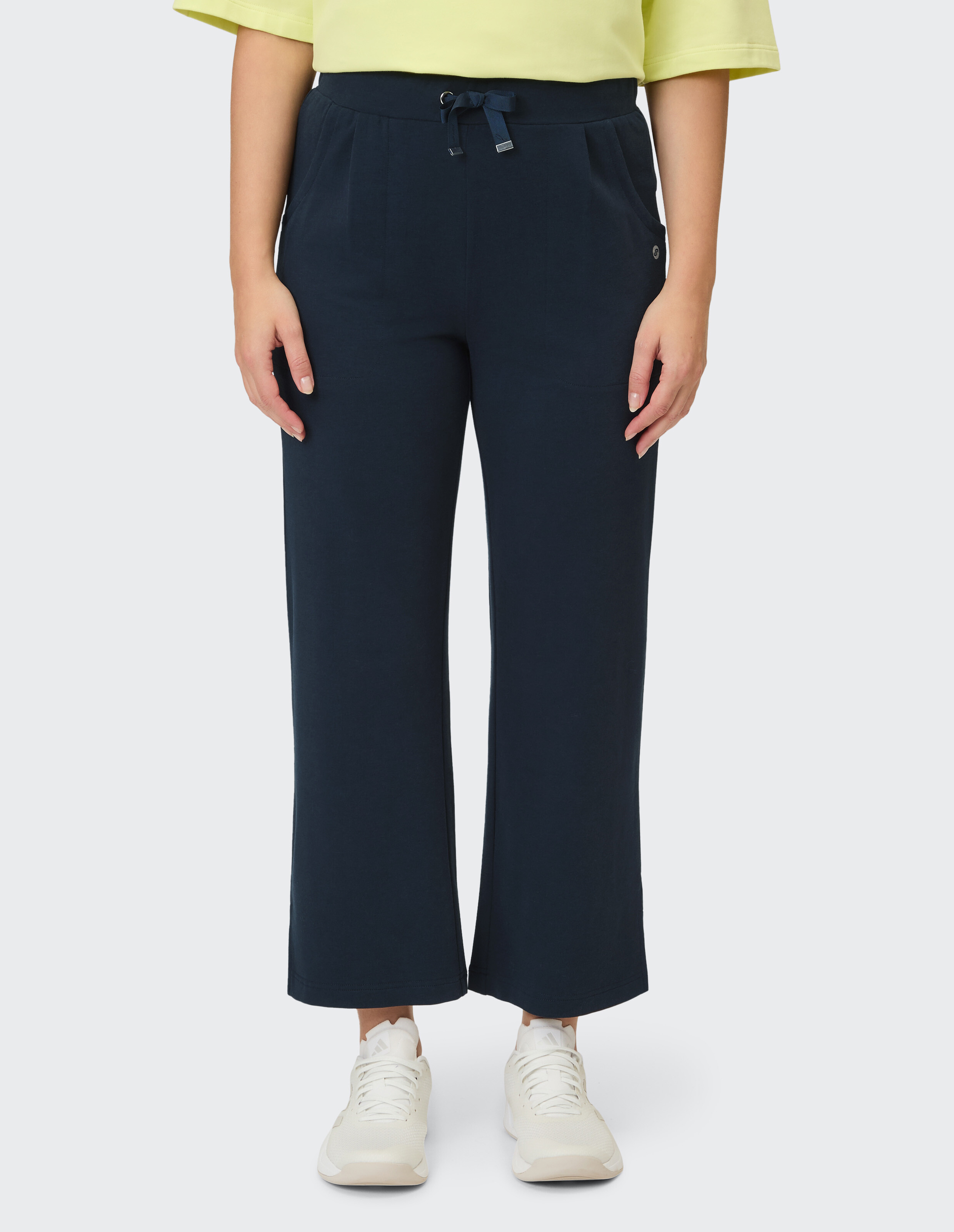 Marineblaue Hose mit weitem Bein und Kordelzug in der Taille, gepaart mit weißen Turnschuhen.