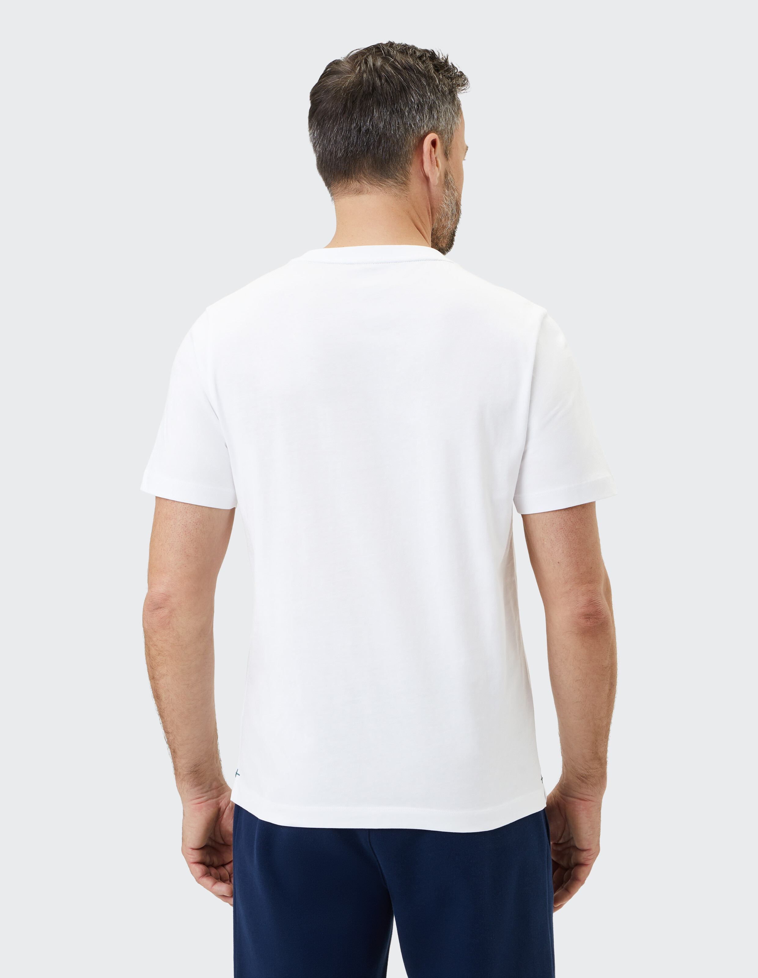 Mann trägt ein klassisches weißes T-Shirt mit Rundhalsausschnitt, Rückansicht, lässiger Stil.