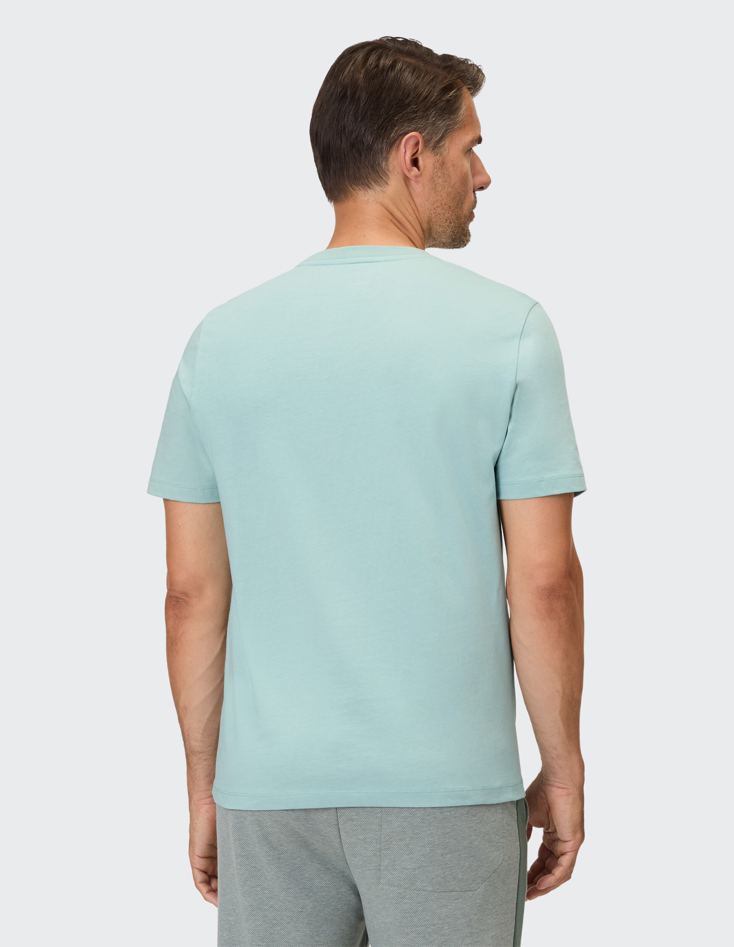 Ein Mann trägt ein hellblaues, kurzärmeliges T-Shirt mit Rundhalsausschnitt.