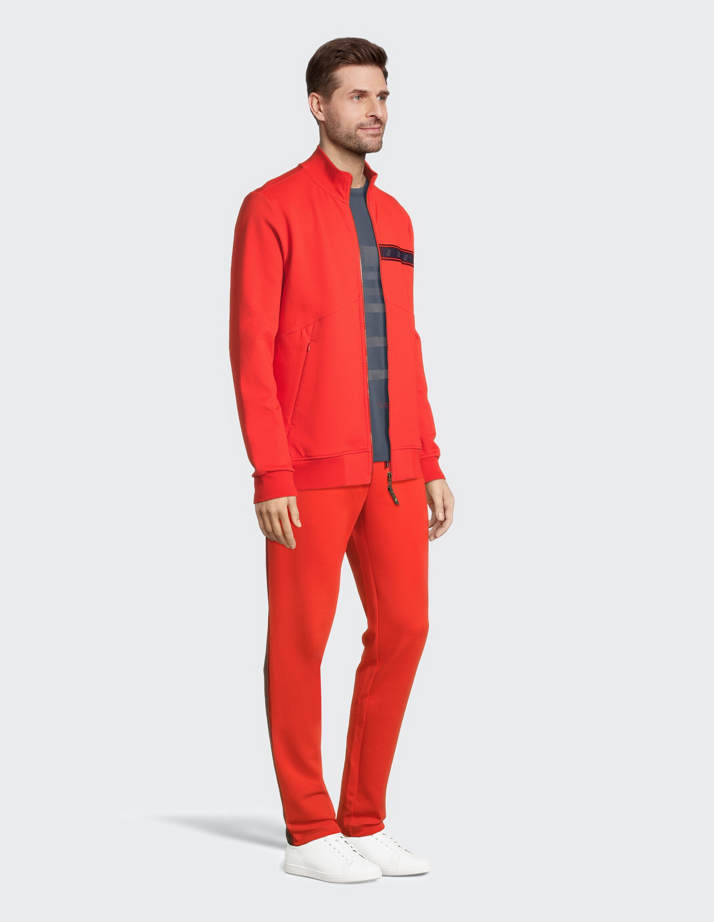 Mann trägt eine rote ELBSAND-Trainingsjacke mit Reißverschluss und eine passende Jogginghose für einen lässigen Stil.