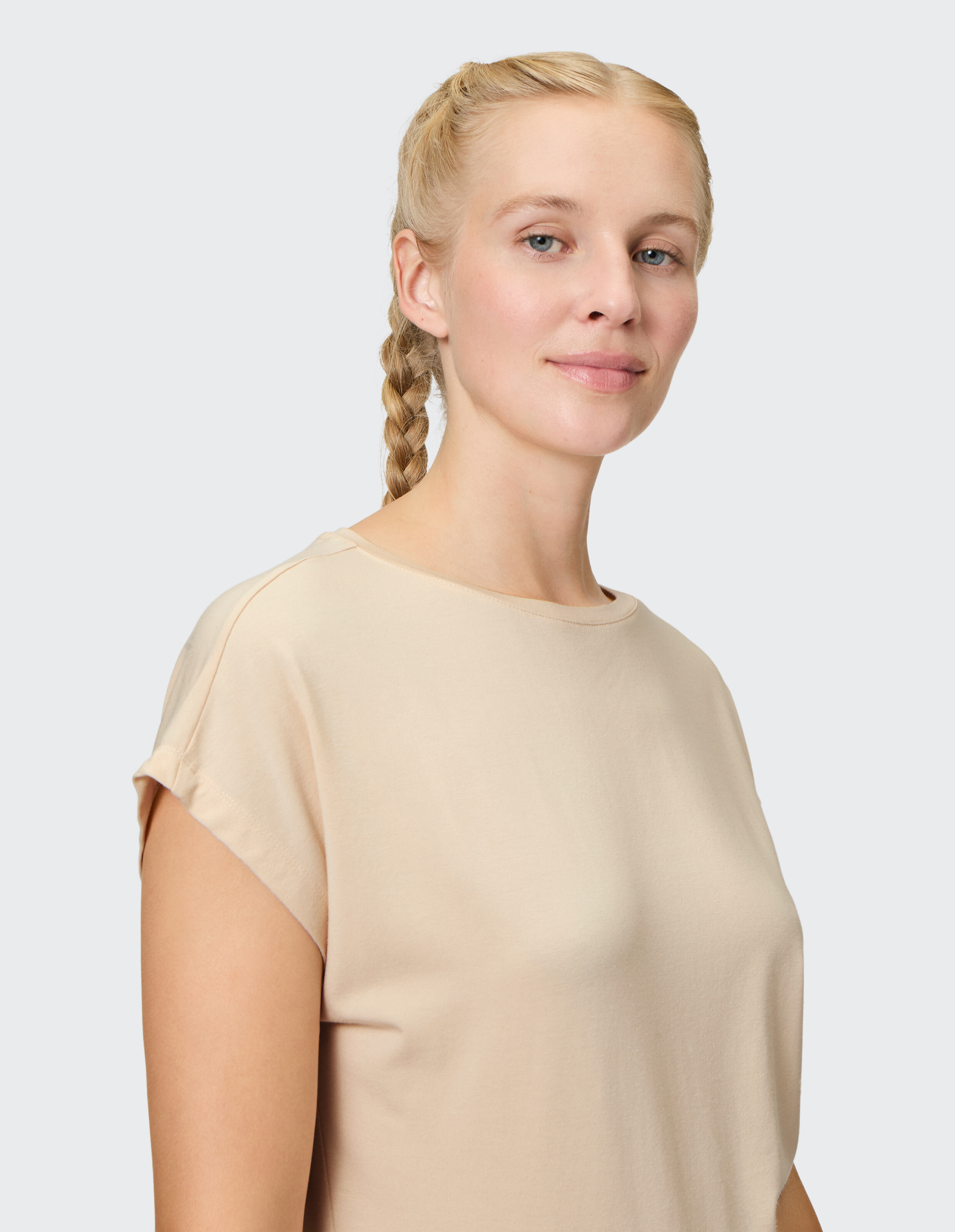 Frau trägt ein beiges Freizeit-T-Shirt mit aufgerollten Ärmeln, perfekt für bequeme Loungewear.