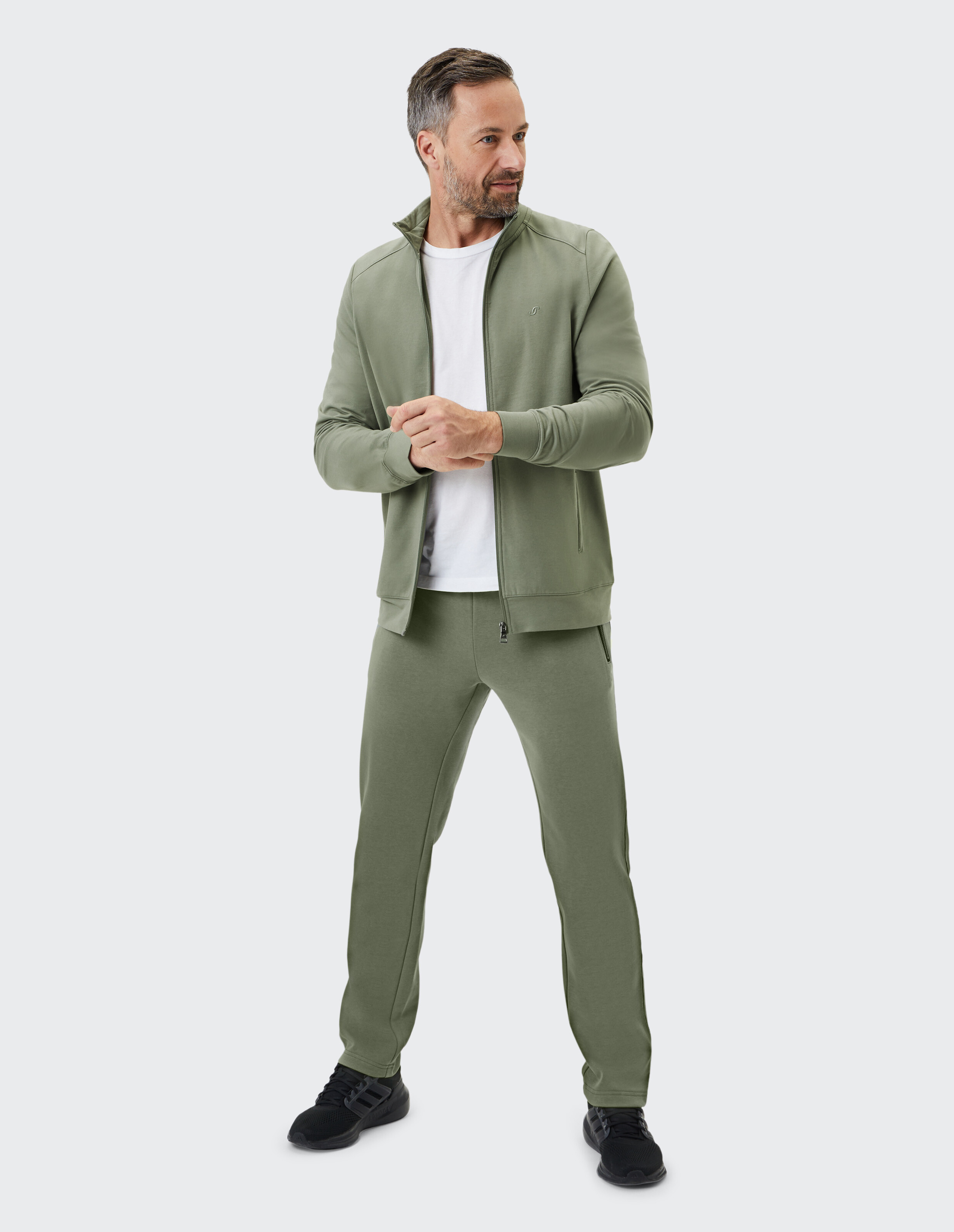 Grüne Unisex-Freizeitjacke mit durchgehendem Reißverschluss, zwei Reißverschlusstaschen und hohem Kragen aus leichtem Material.