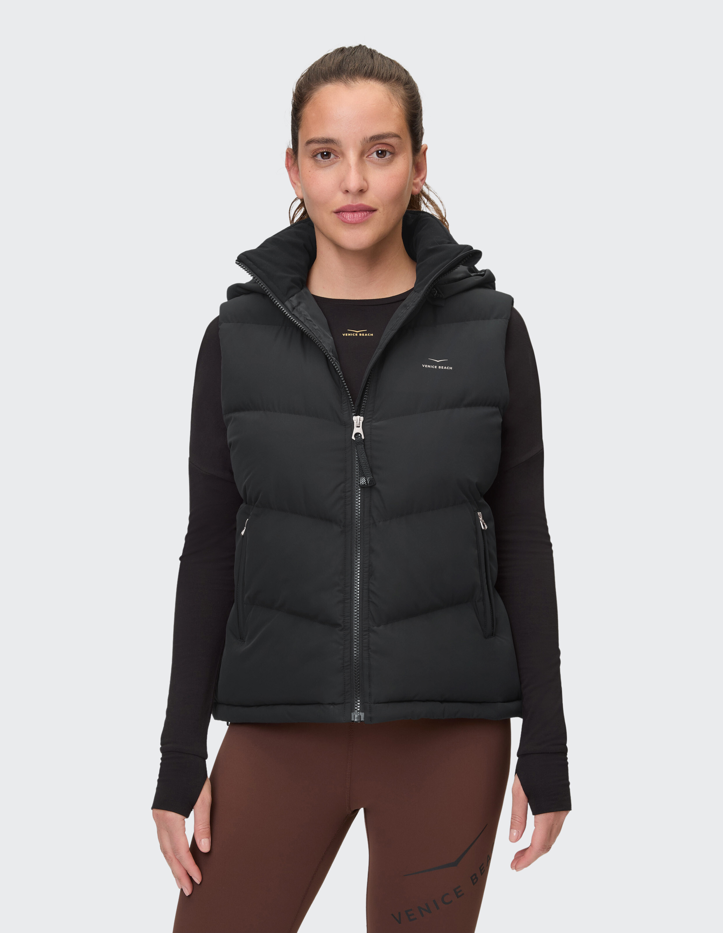 Frau trägt eine schwarze gesteppte Kapuzenweste für lässigen Outdoor-Stil.