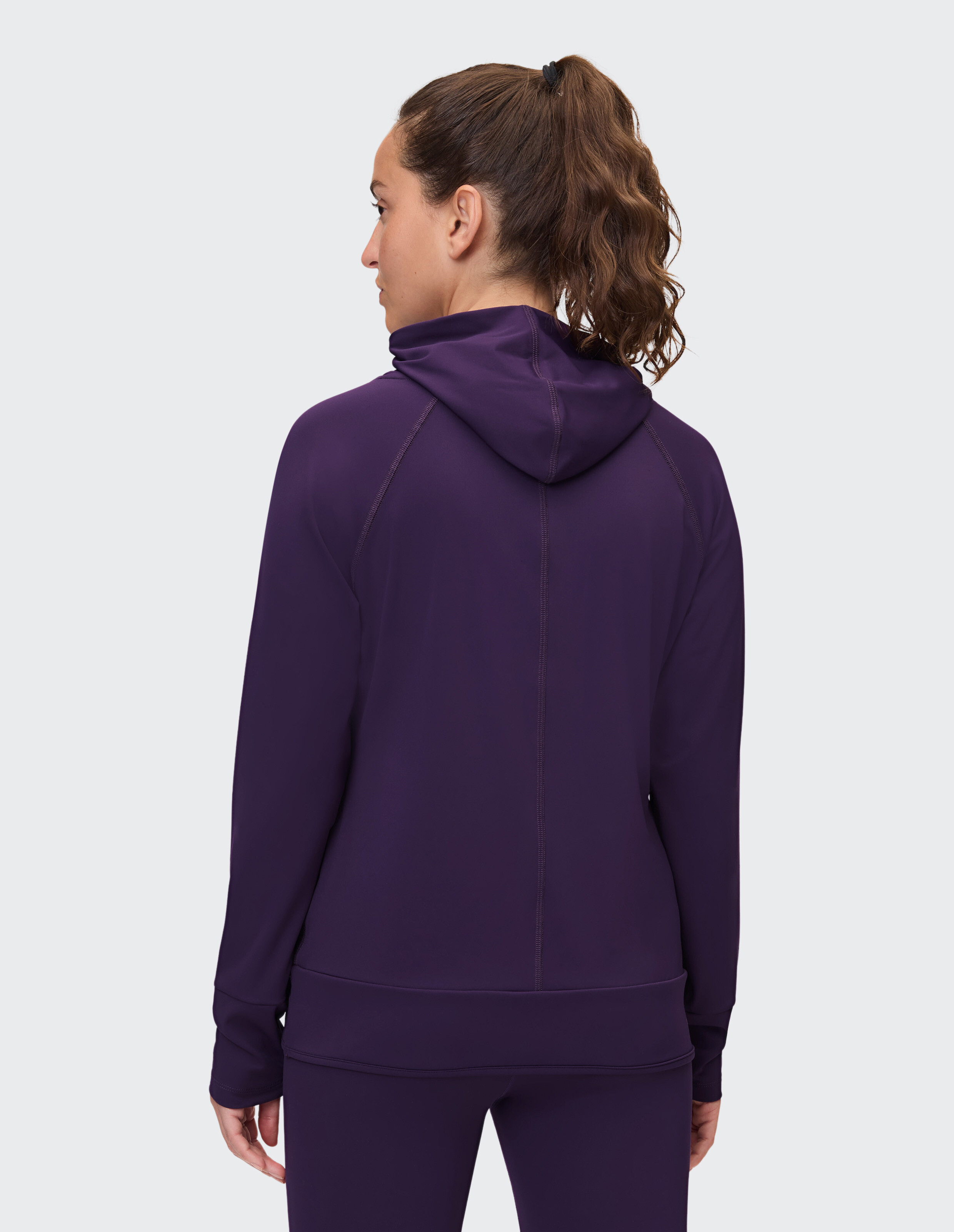 Rückansicht einer Frau in einem lila Kapuzenpullover, die einen gemütlichen und stilvollen Casual-Look präsentiert.