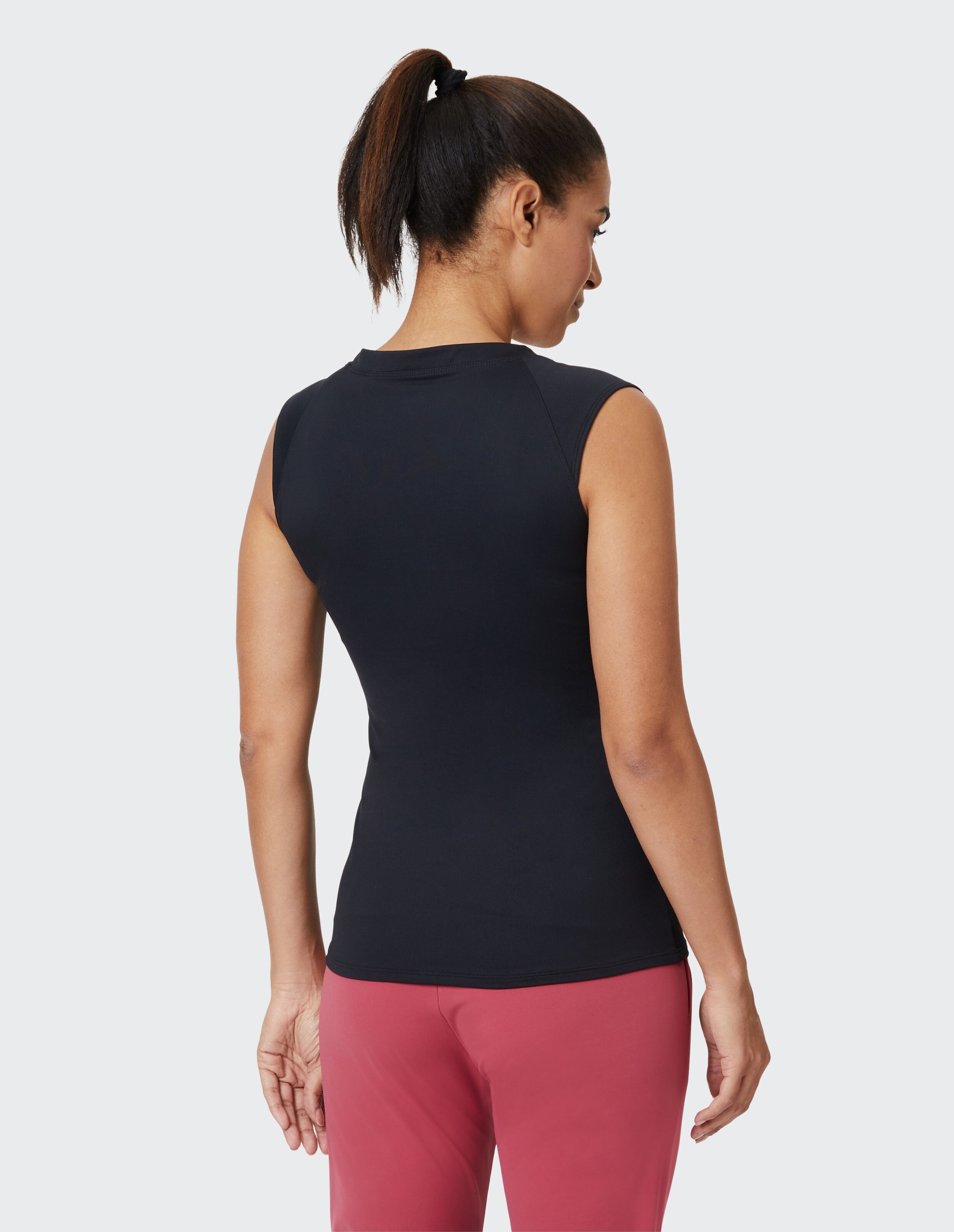Frau trägt ein schwarzes ärmelloses Oberteil und eine rote Hose für einen lässigen, bequemen Stil.