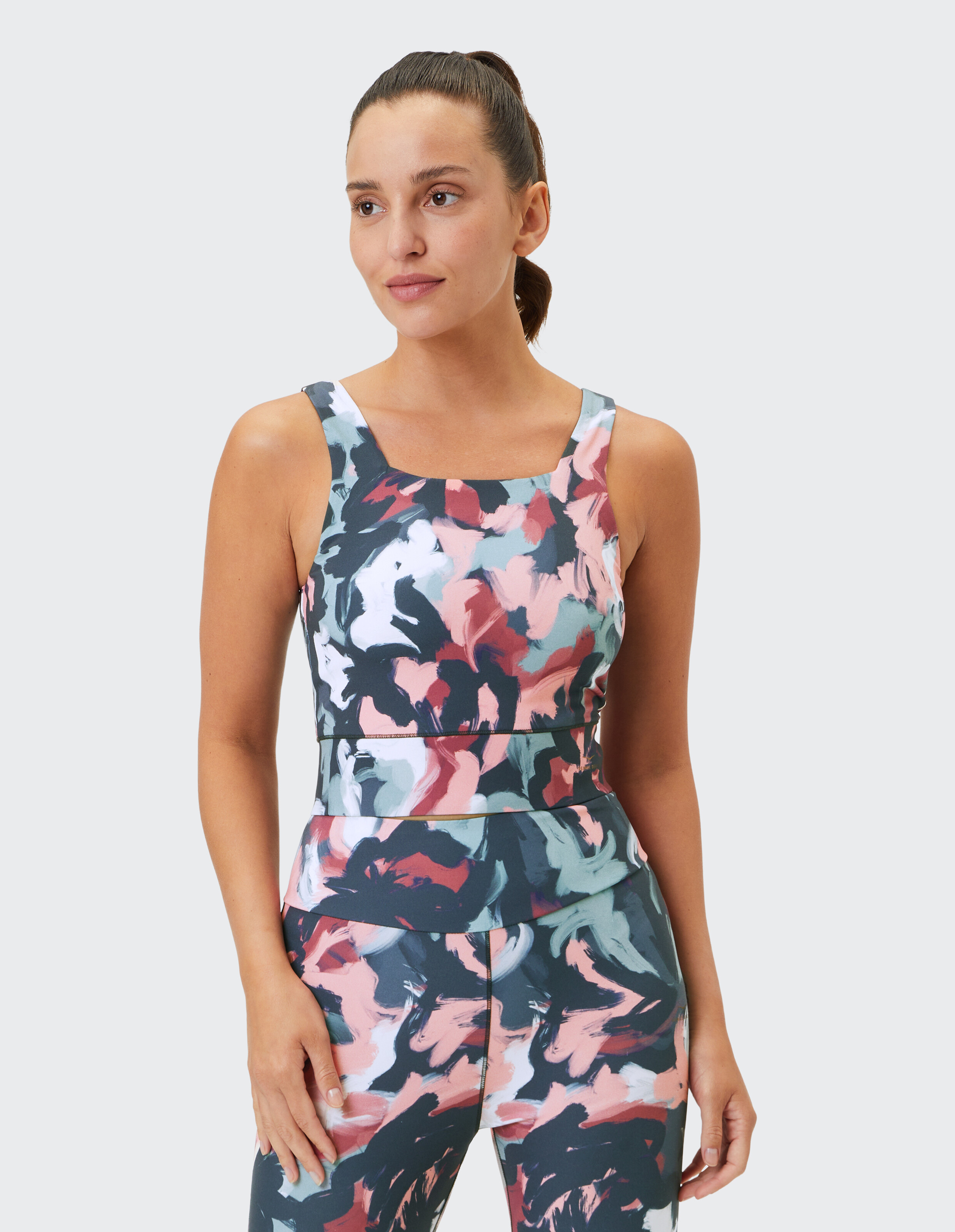 Frau trägt das Venice Beach Top Jeanna mit einem farbenfrohen abstrakten Print für lässige Aktivkleidung.