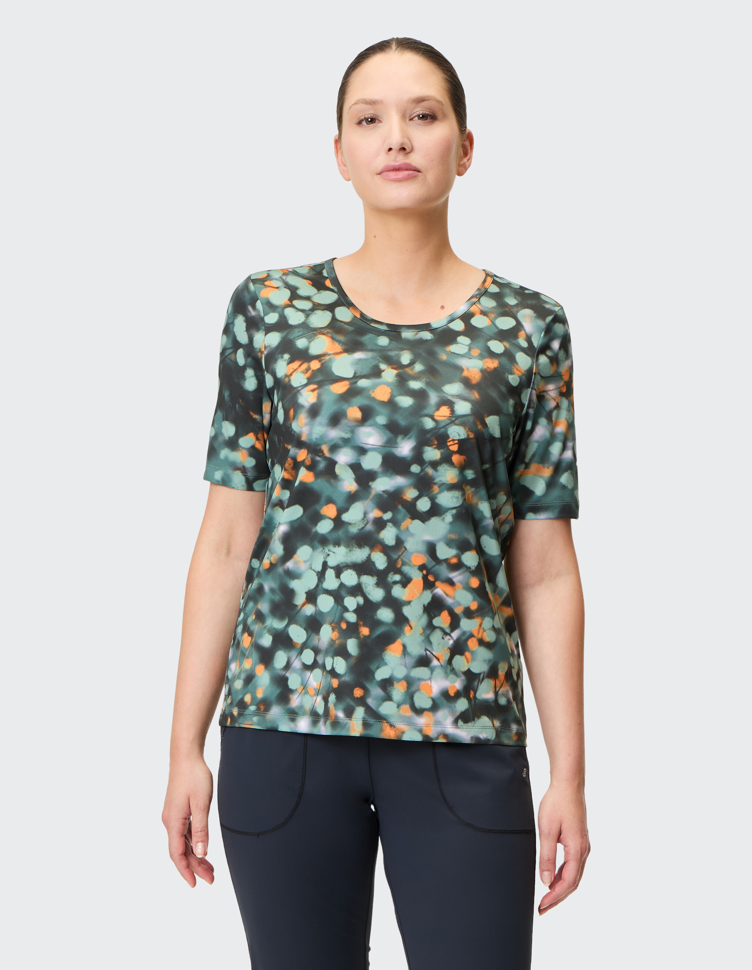 Kurzarmshirt mit abstraktem Punktmuster in Grün, Orange und Schwarz, Rundhalsausschnitt, stilvoll und modern gestaltet.