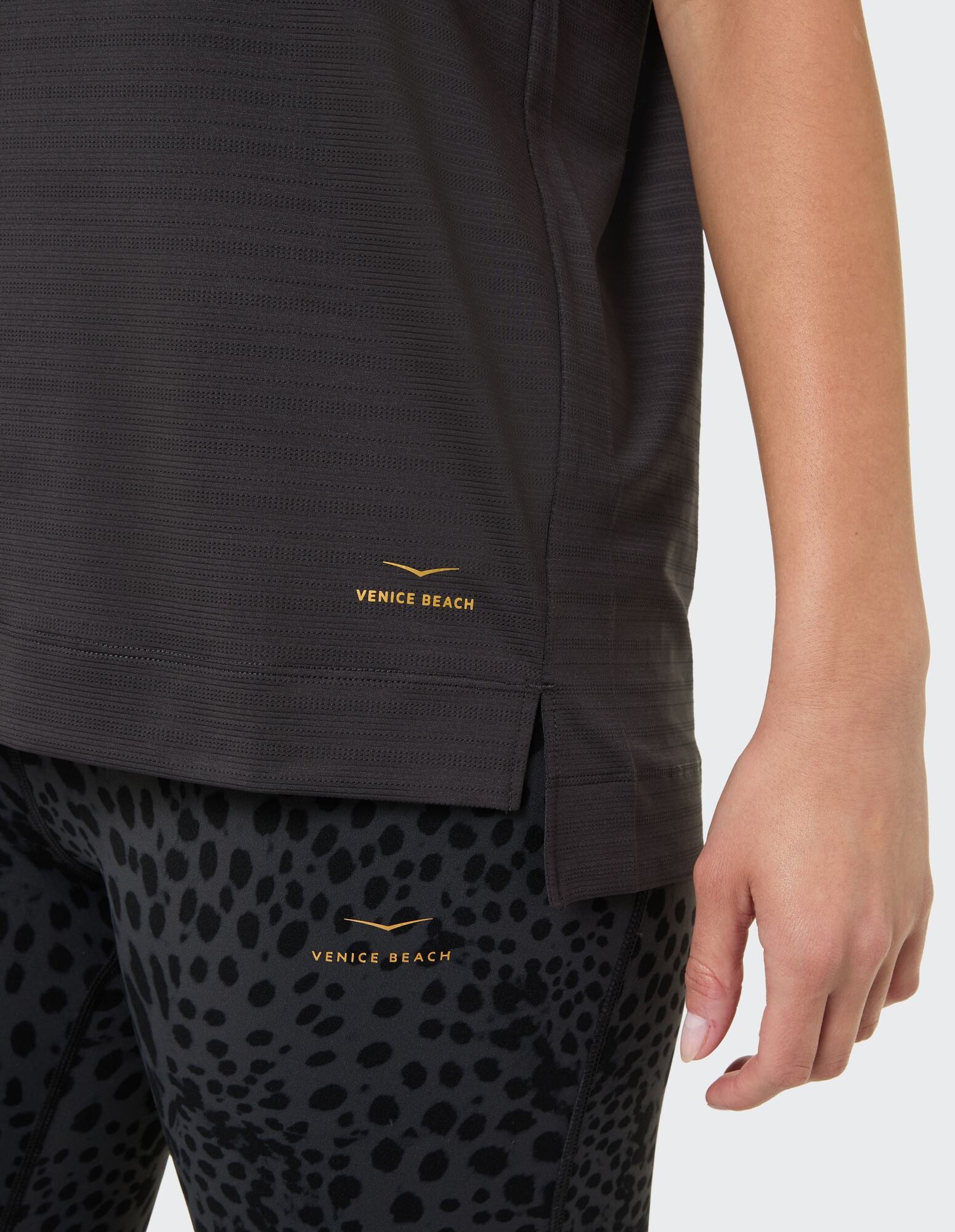 Nahaufnahme eines schwarzen strukturierten Oberteils gepaart mit Leggings mit Leopardenmuster.