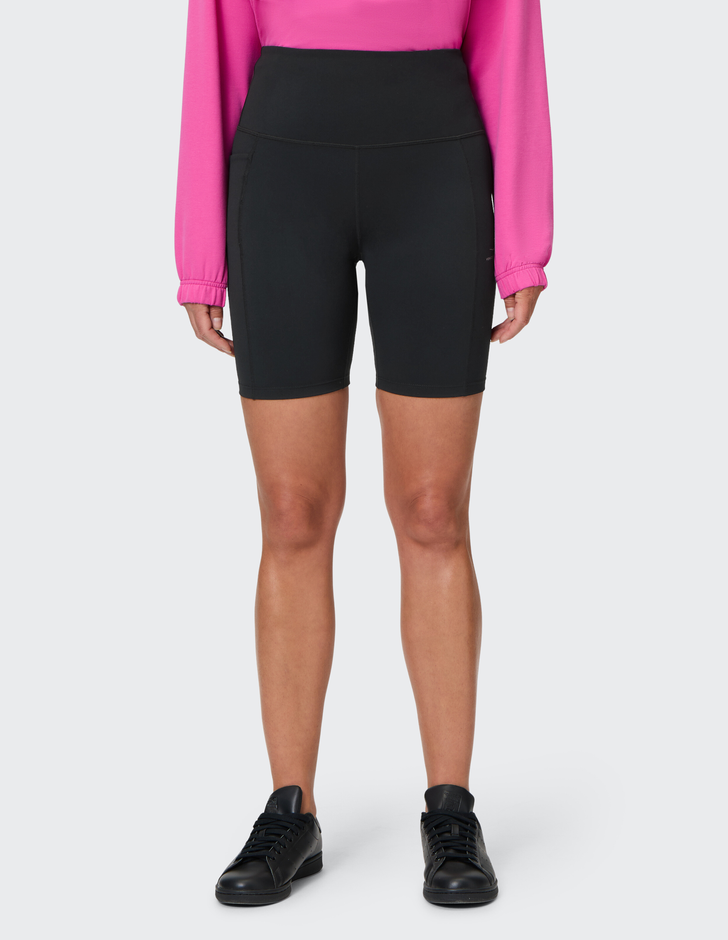 Schwarze Radlershorts mit hoher Taille gepaart mit einem rosa Langarmshirt.