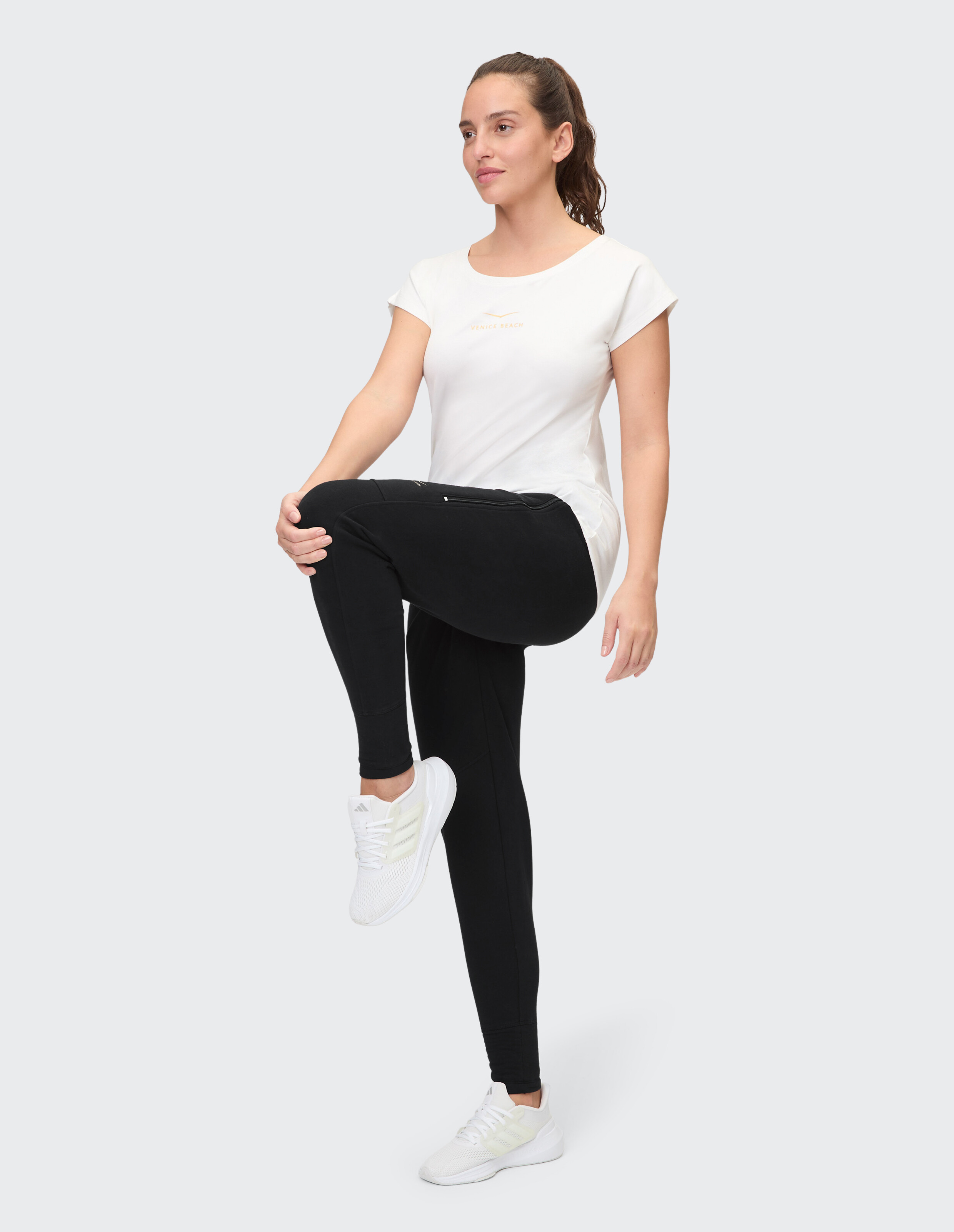 Frau trägt ein weißes T-Shirt und schwarze Leggings für einen bequemen, lässigen Look.