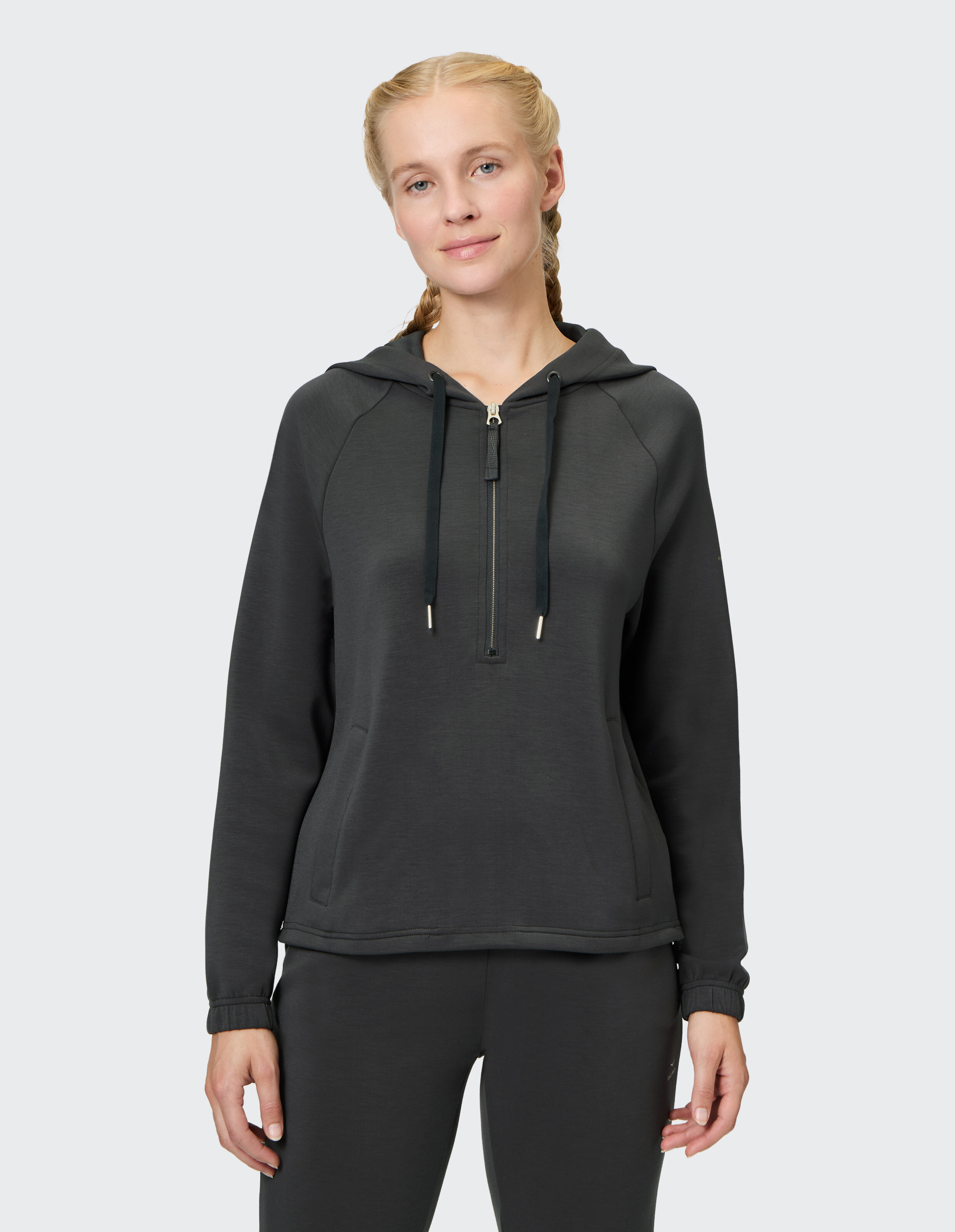 Frau trägt einen kuscheligen dunkelgrauen Kapuzenpullover mit halbem Reißverschluss für lässige Loungewear.
