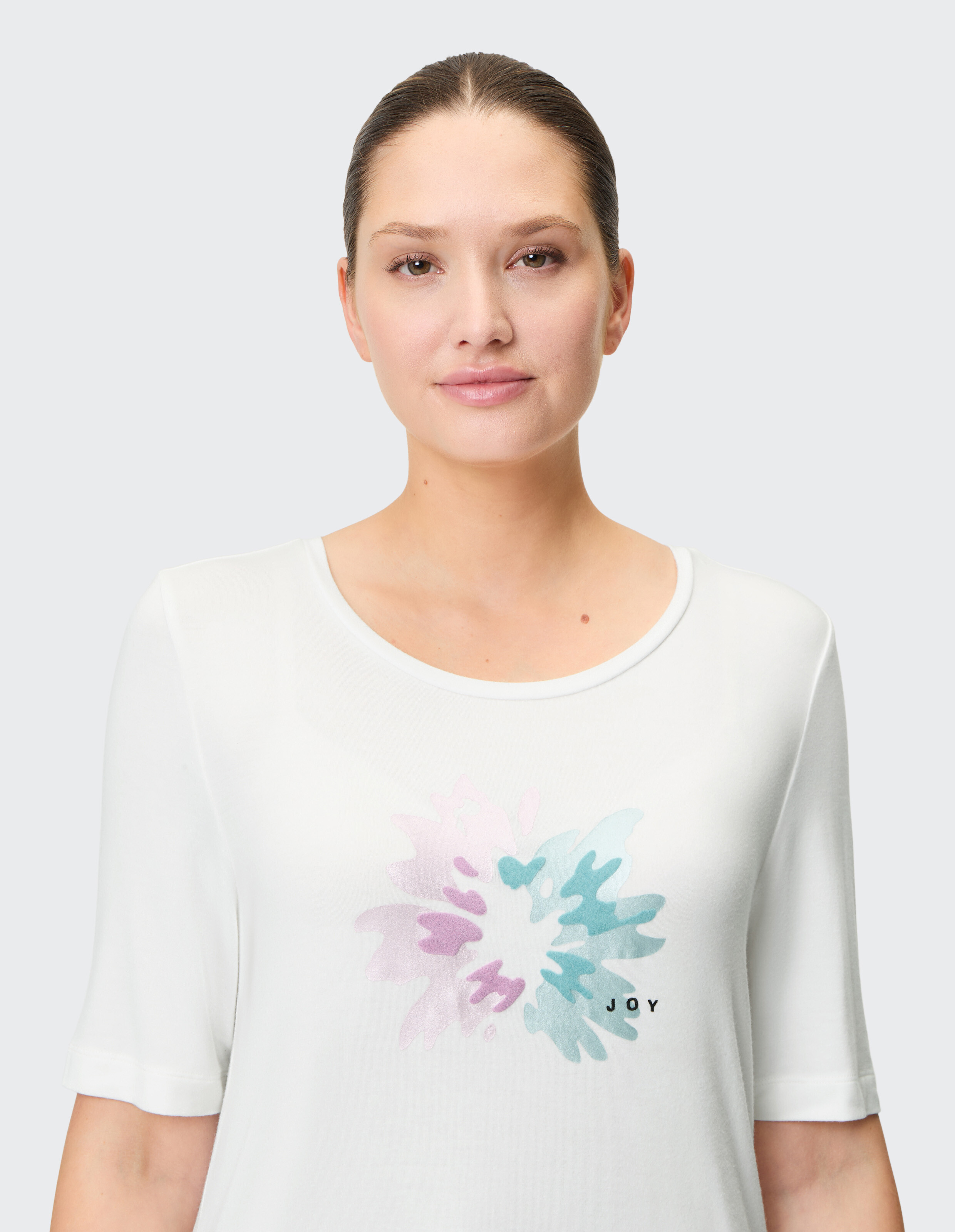Weißes, lässiges T-Shirt mit buntem Blumendruck und „JOY“-Schriftzug, perfekt zum entspannten Tragen.