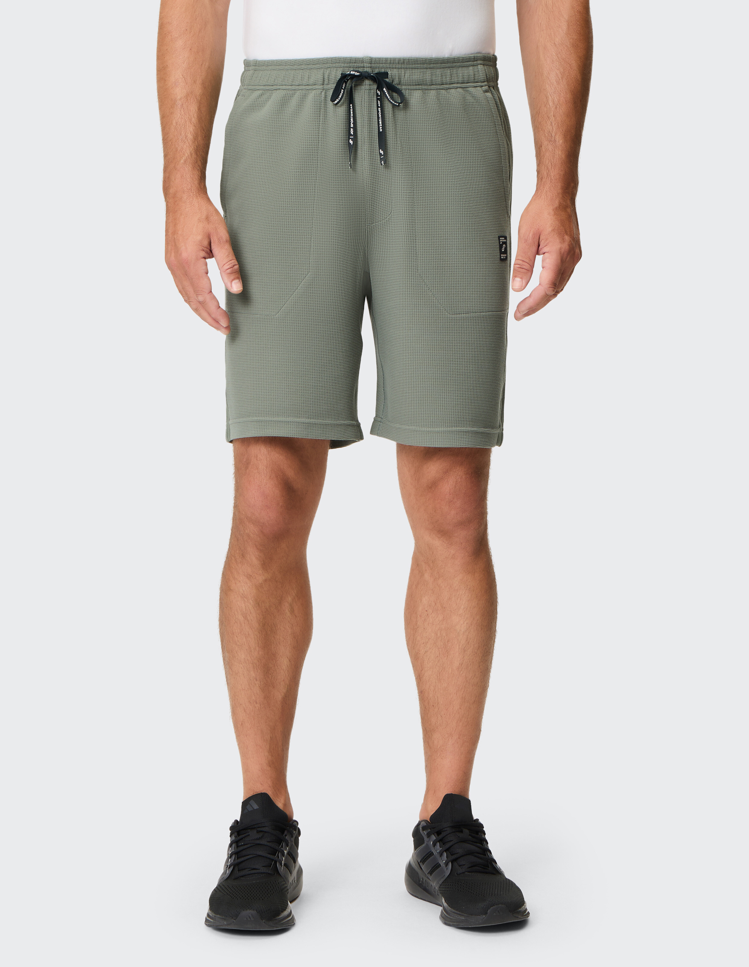 Grüne, karierte Shorts mit elastischem Bund, dunklem Zugband und Seitentaschen, ideal für Freizeit und sportliche Aktivitäten.