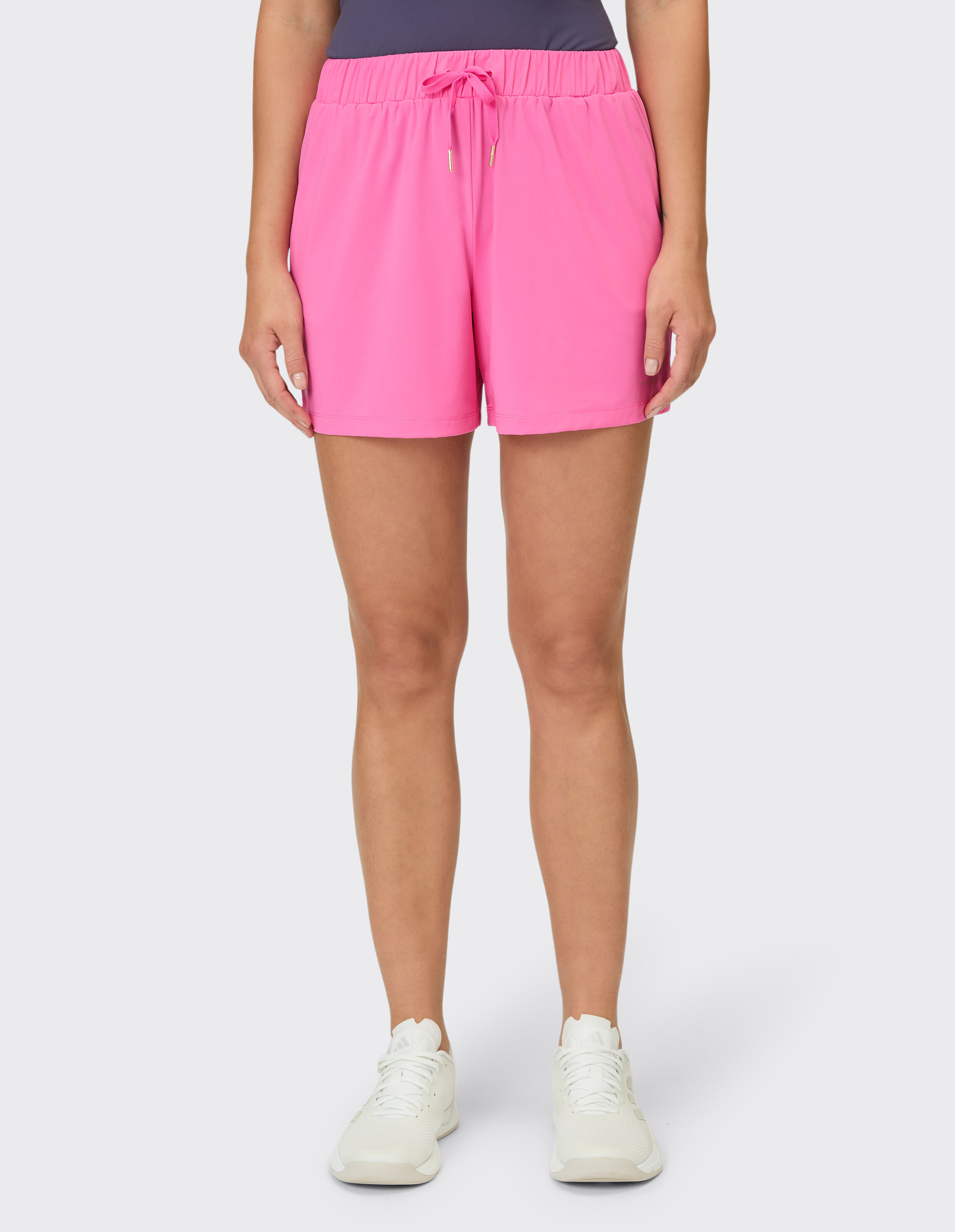 Frau trägt leuchtend rosa lässige Shorts mit Kordelzug zum Faulenzen oder als Sportkleidung.