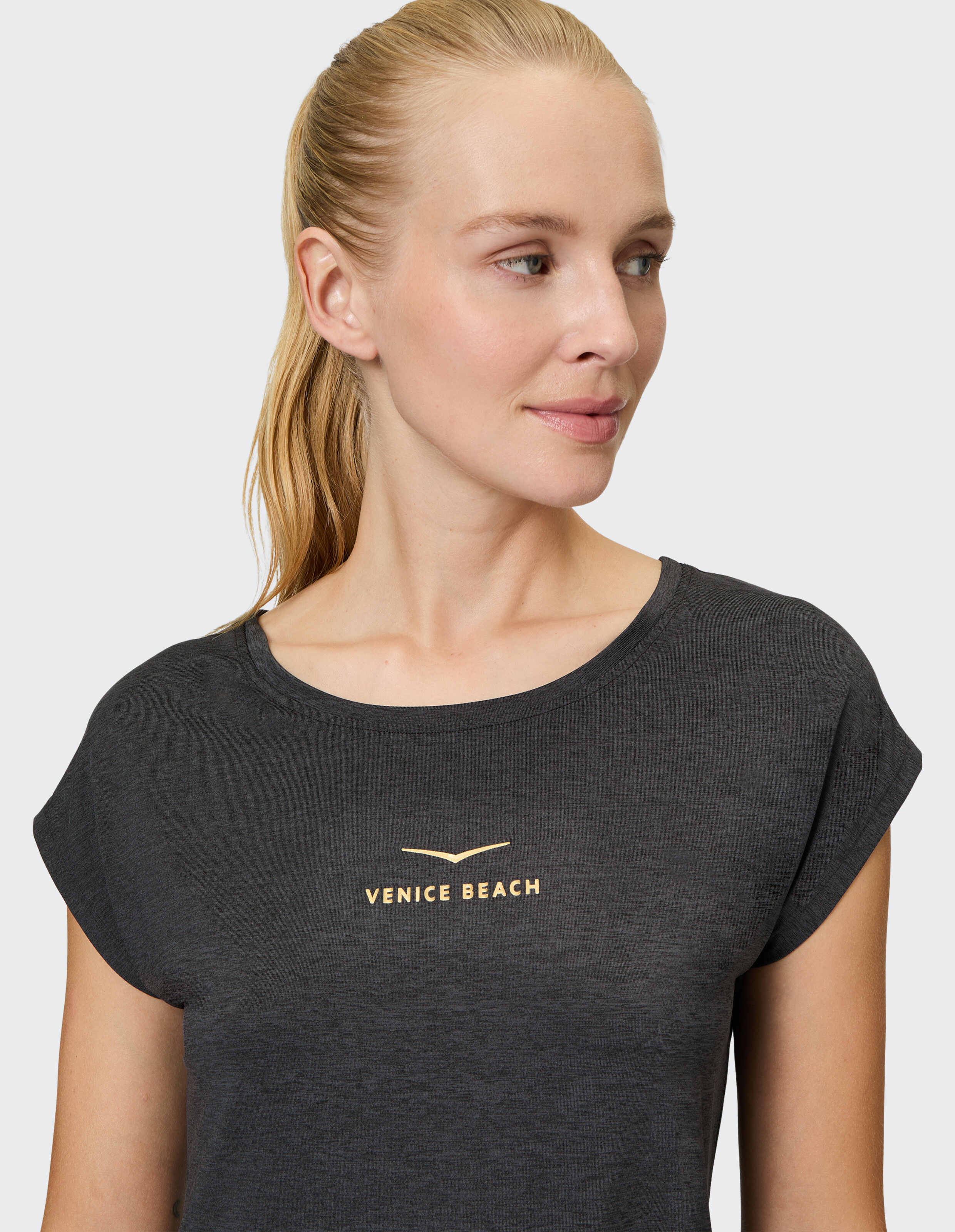 Frau trägt ein dunkelgraues, bequemes, lässiges Venice Beach-T-Shirt zum Entspannen.