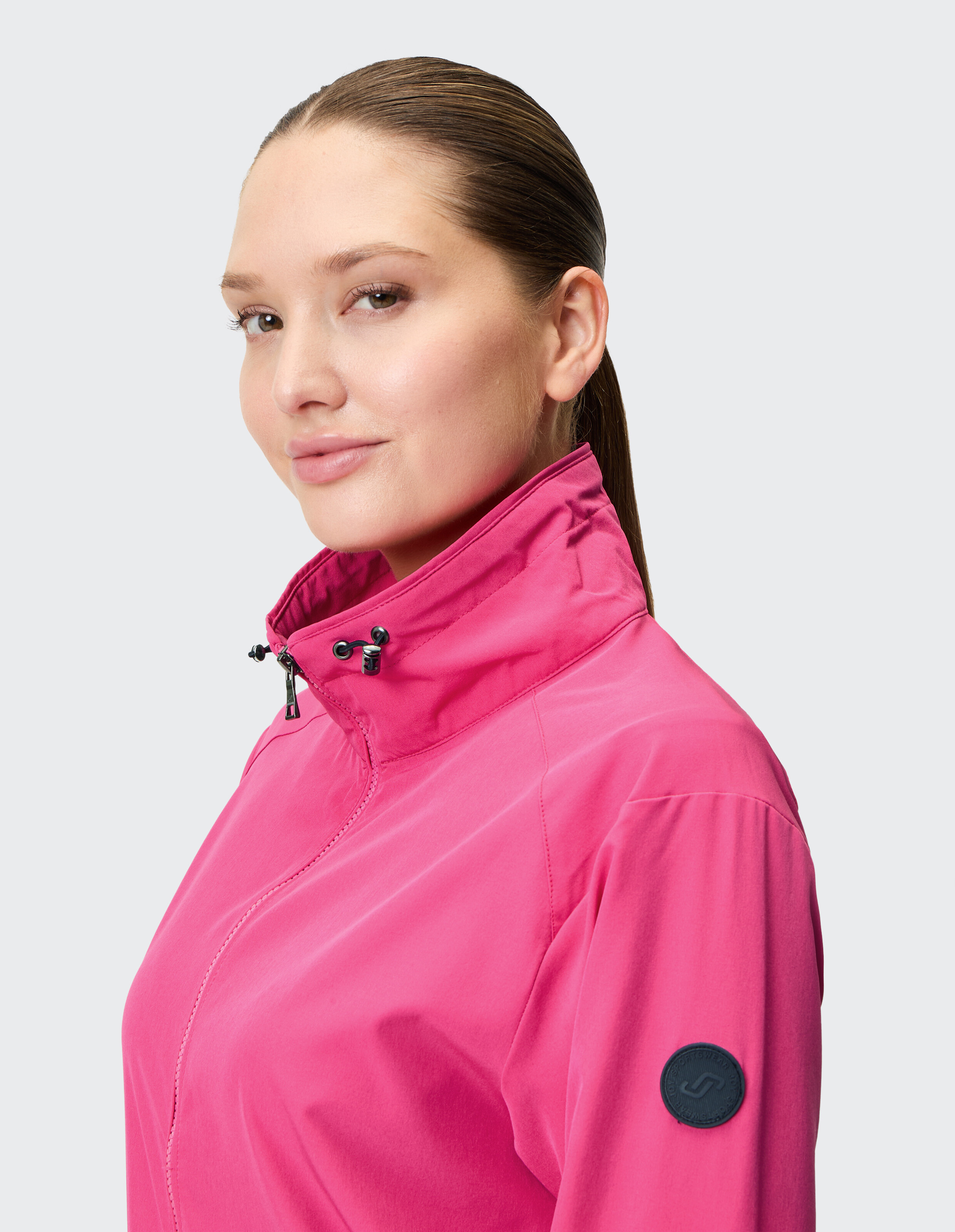 Frau trägt eine leuchtend rosa lässige Jacke mit Reißverschluss und hohem Kragen.