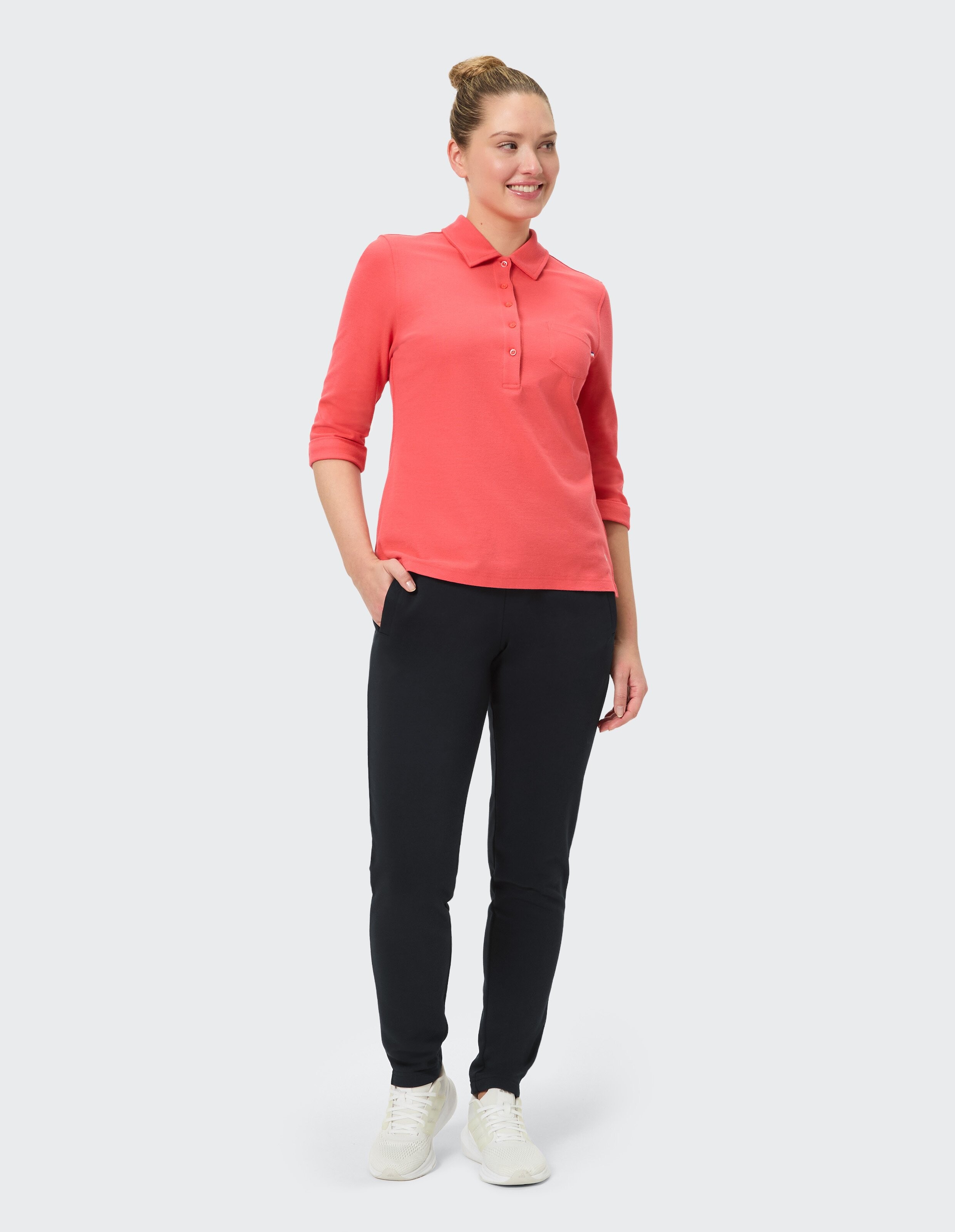 Frau in rosa gestreiftem Shirt und schwarzer Hose macht eine Boxbewegung, steht breitbeinig, Blick konzentriert nach vorne.