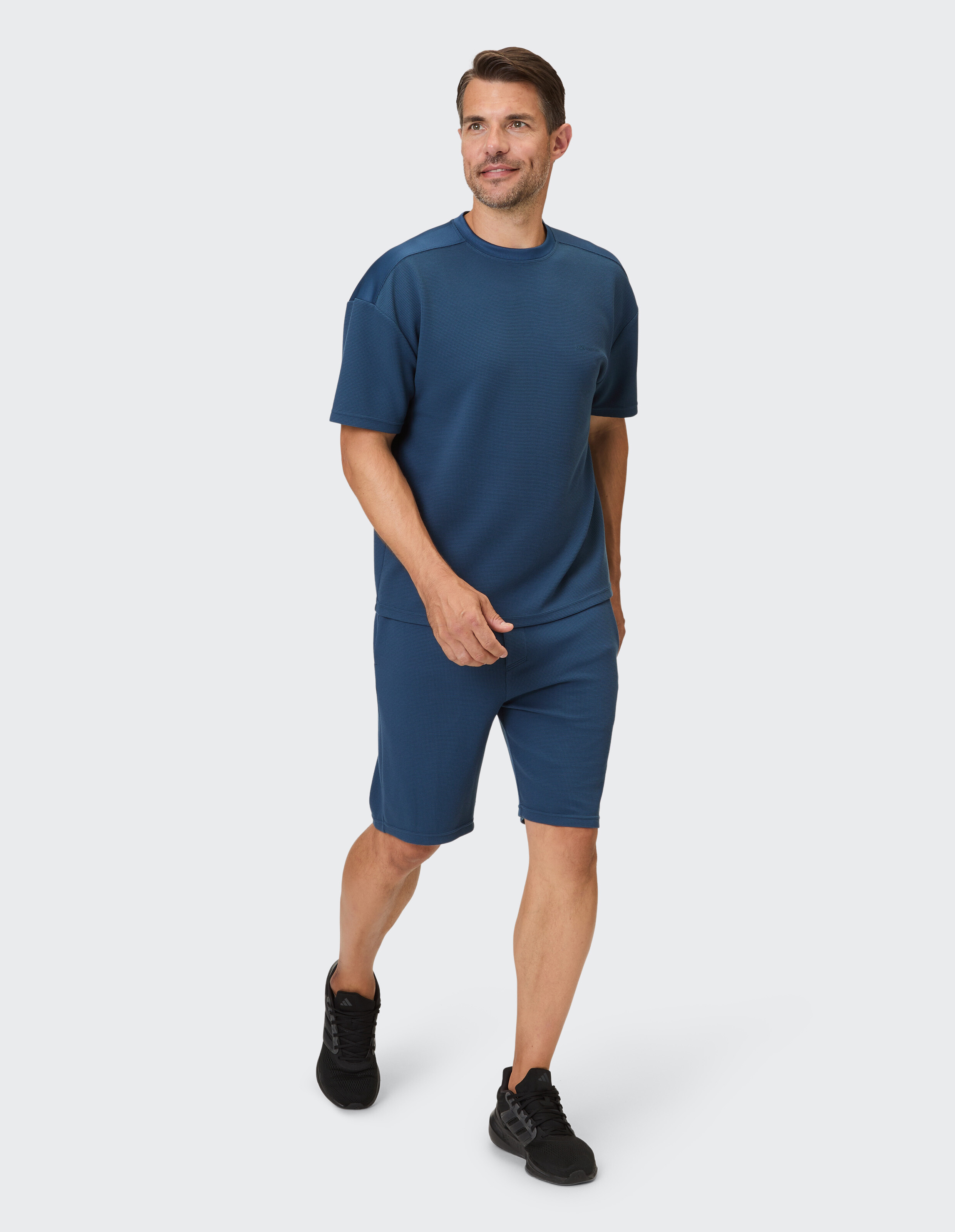 Ein Mann trägt ein marineblaues Set aus einem kurzärmeligen Oberteil und Shorts mit Waffelstruktur.
