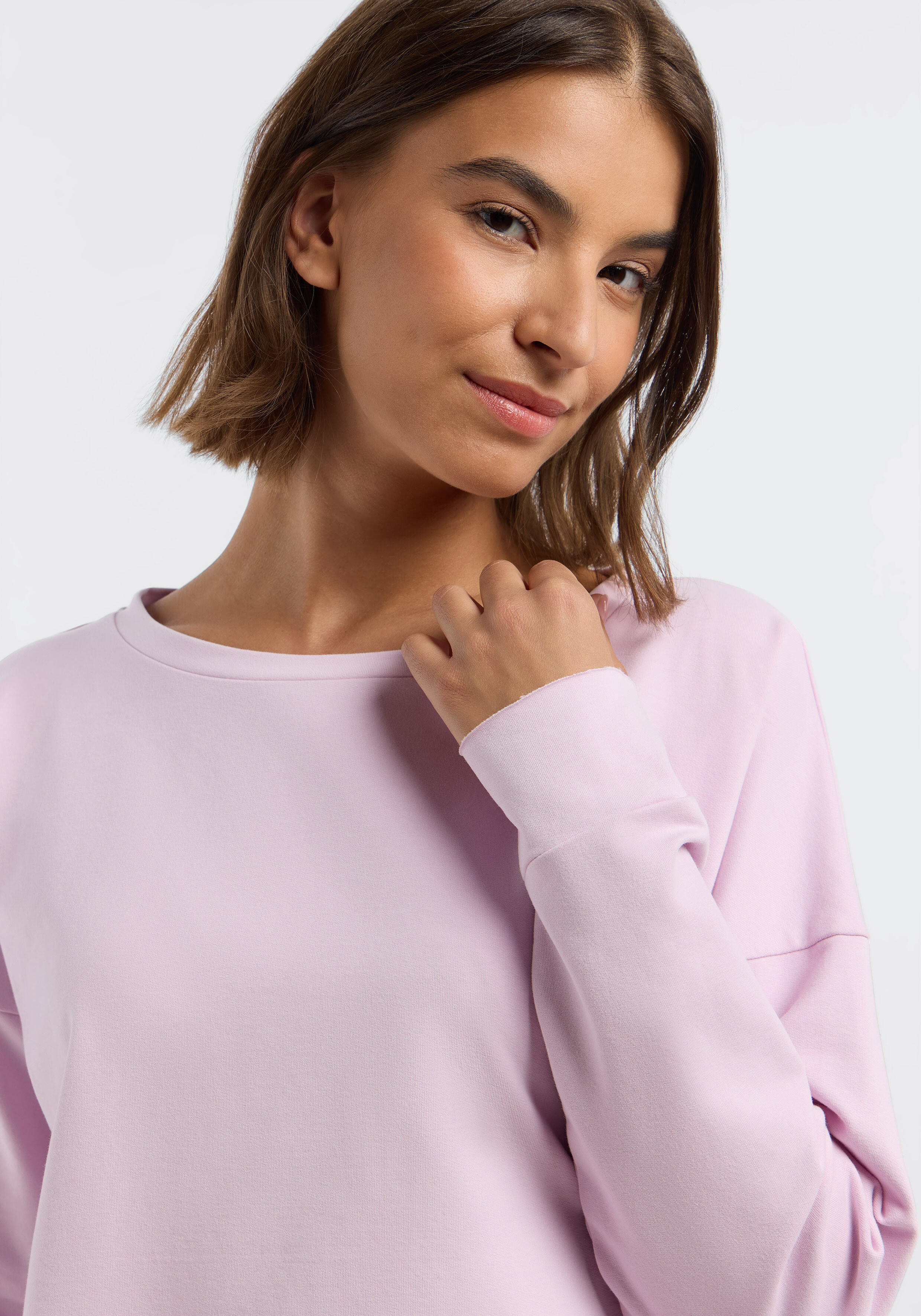 Frau trägt ein gemütliches hellrosa lässiges Sweatshirt zum Faulenzen oder Reisen.